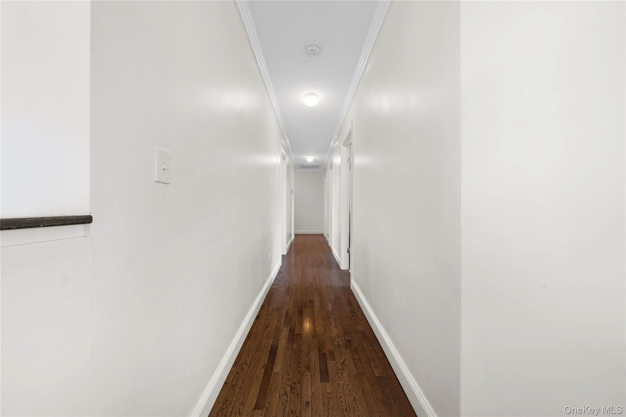 Hall with crown molding and dark wood finished floors Hall with crown molding and dark wood finished floors