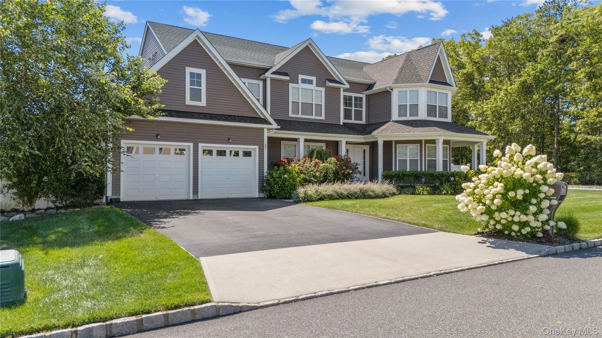 View of front facade featuring driveway, covered porch, an attached garage, a shingled roof, and a front lawn View of front facade featuring driveway, covered porch, an attached garage, a shingled roof, and a front lawn