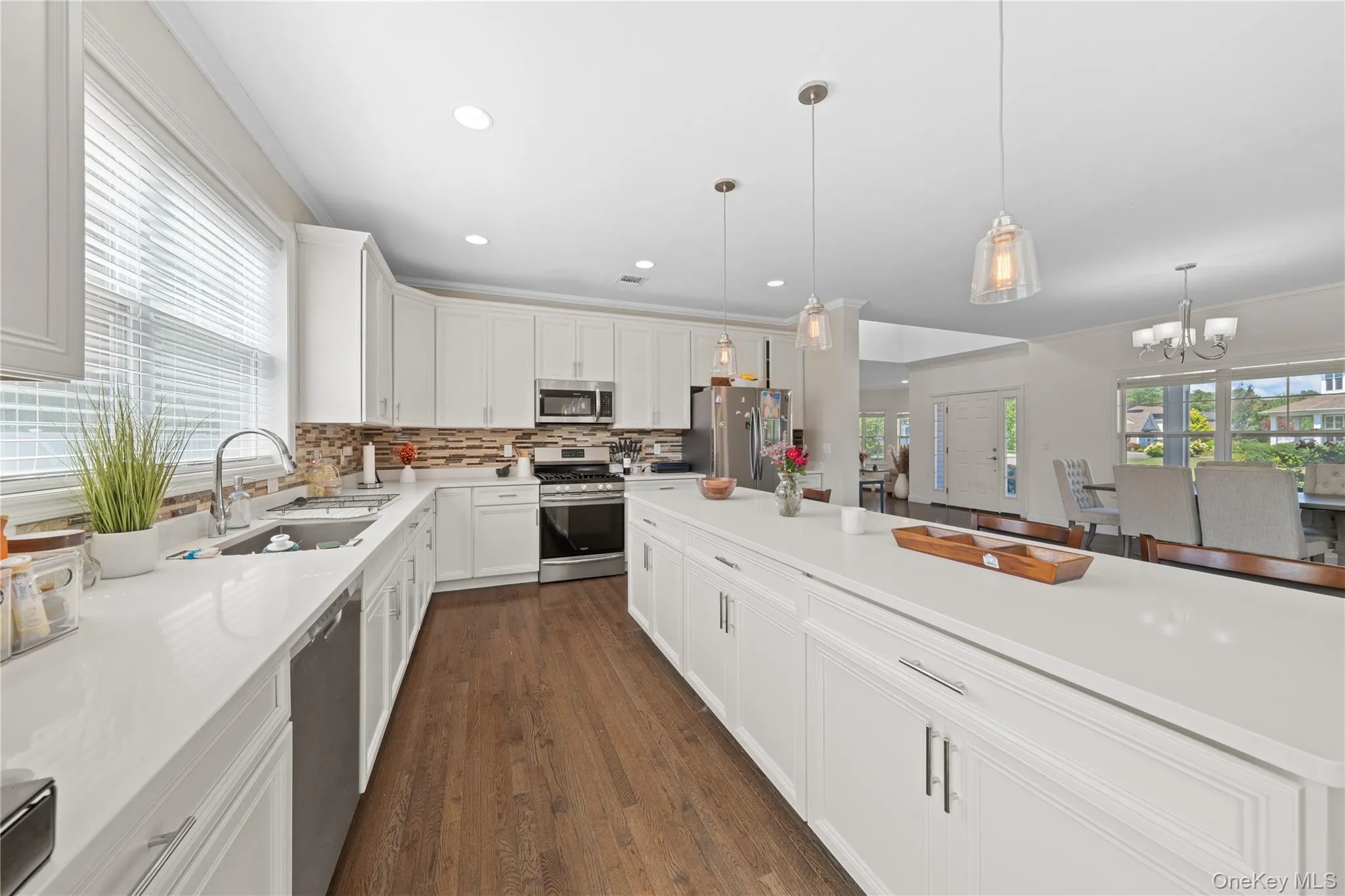 Kitchen with white cabinetry, stainless steel appliances, backsplash, decorative light fixtures, and recessed lighting Kitchen with white cabinetry, stainless steel appliances, backsplash, decorative light fixtures, and recessed lighting