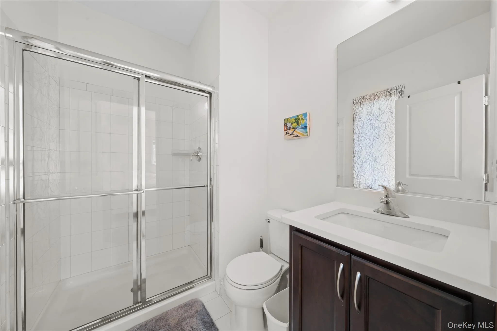 Full bath featuring a stall shower, vanity, and light tile patterned flooring Full bath featuring a stall shower, vanity, and light tile patterned flooring