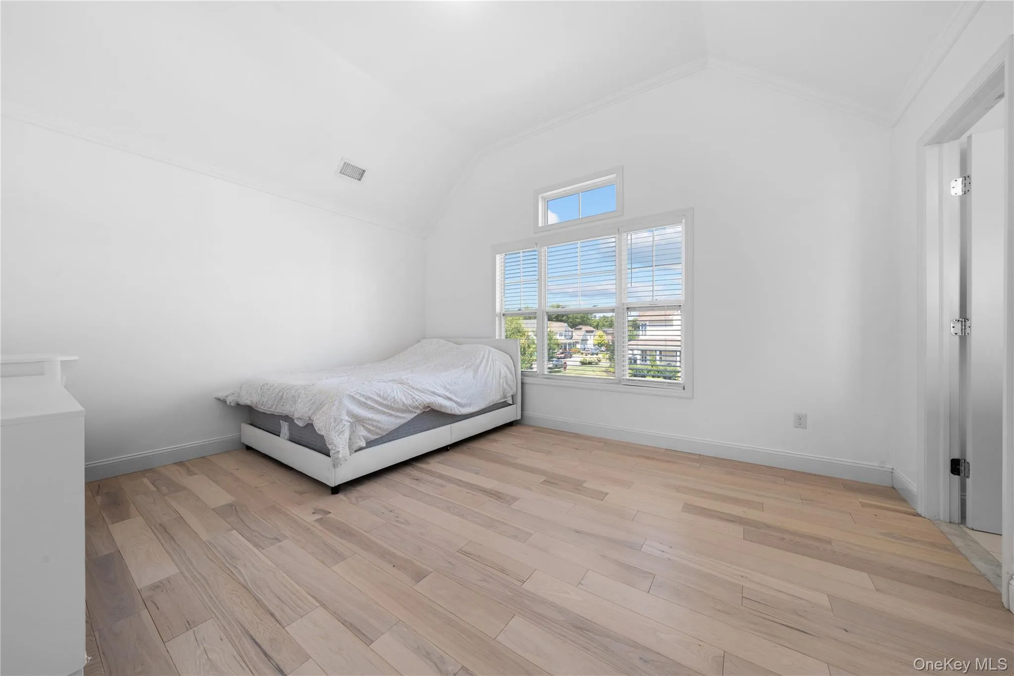 Bedroom featuring light wood finished floors, high vaulted ceiling, and ornamental molding Bedroom featuring light wood finished floors, high vaulted ceiling, and ornamental molding