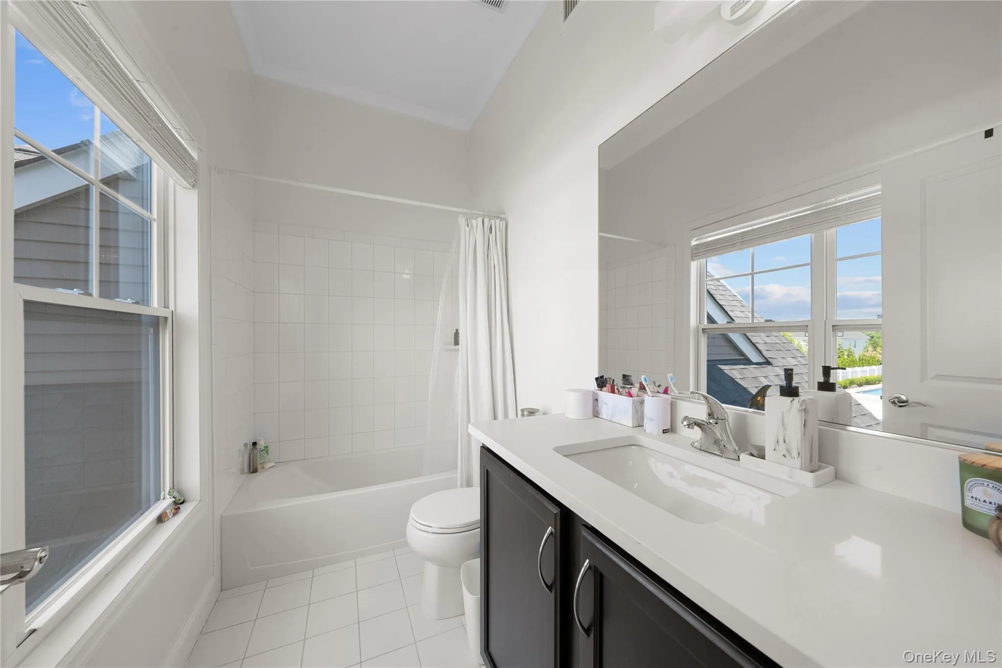 Bathroom with shower / bath combo with shower curtain, vanity, and light tile patterned floors Bathroom with shower / bath combo with shower curtain, vanity, and light tile patterned floors