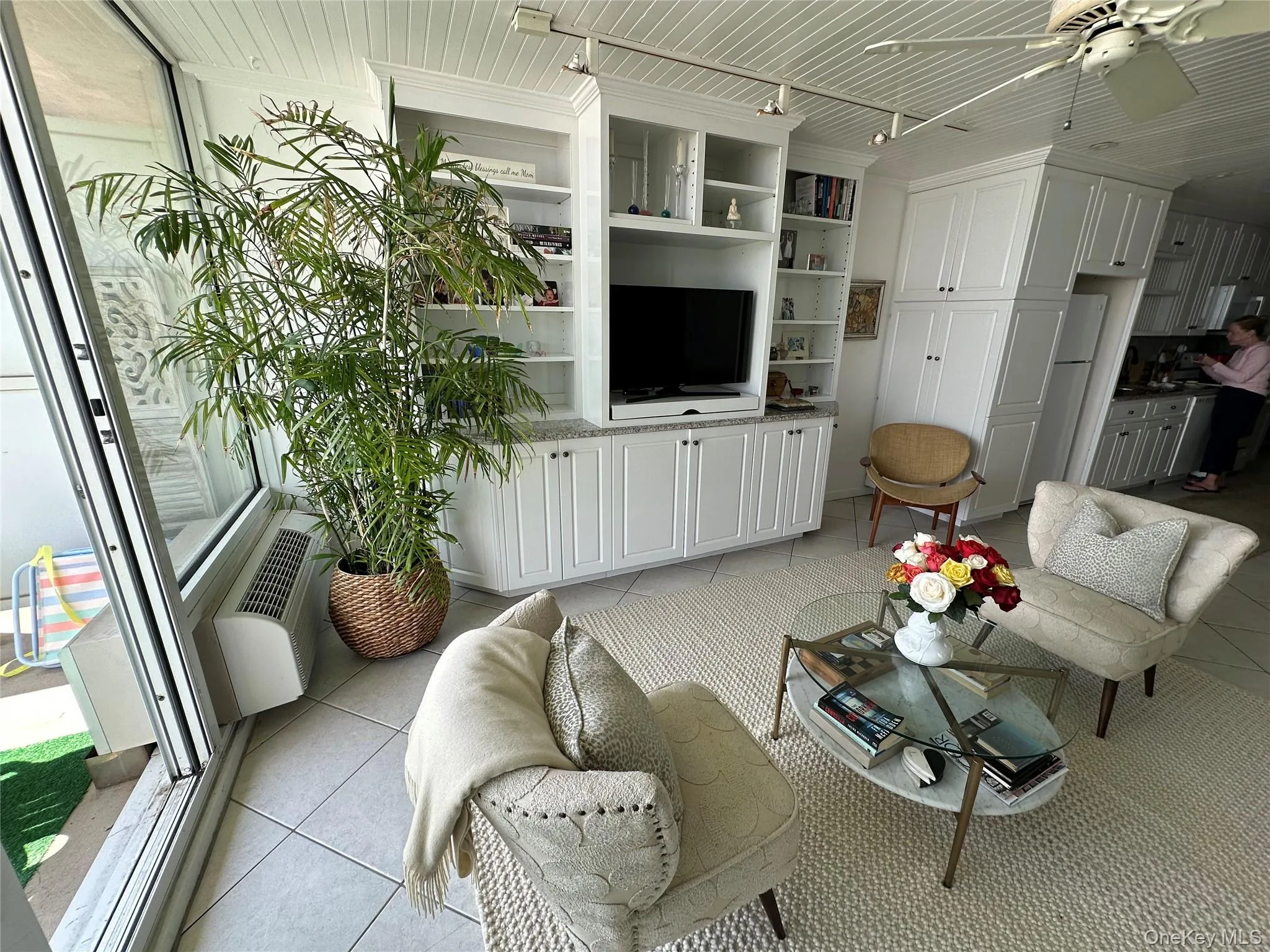 Living area with light tile patterned floors, rail lighting, a ceiling fan, and a wall mounted air conditioner Living area with light tile patterned floors, rail lighting, a ceiling fan, and a wall mounted air conditioner