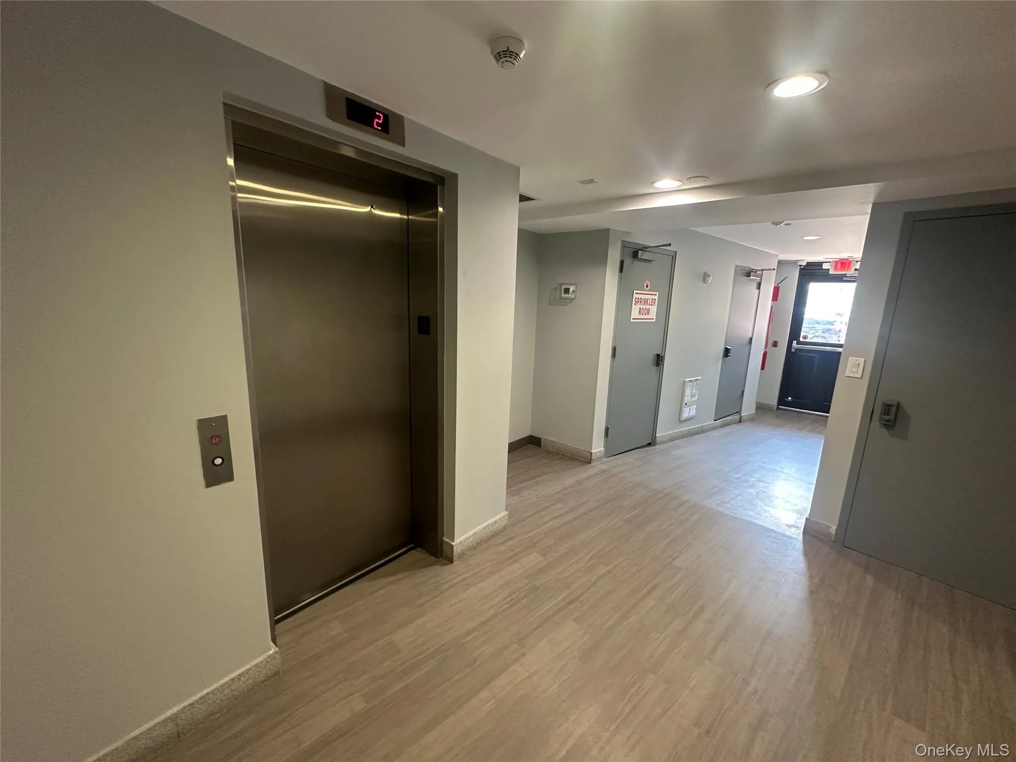 Corridor with elevator, light wood-style floors, and recessed lighting Corridor with elevator, light wood-style floors, and recessed lighting
