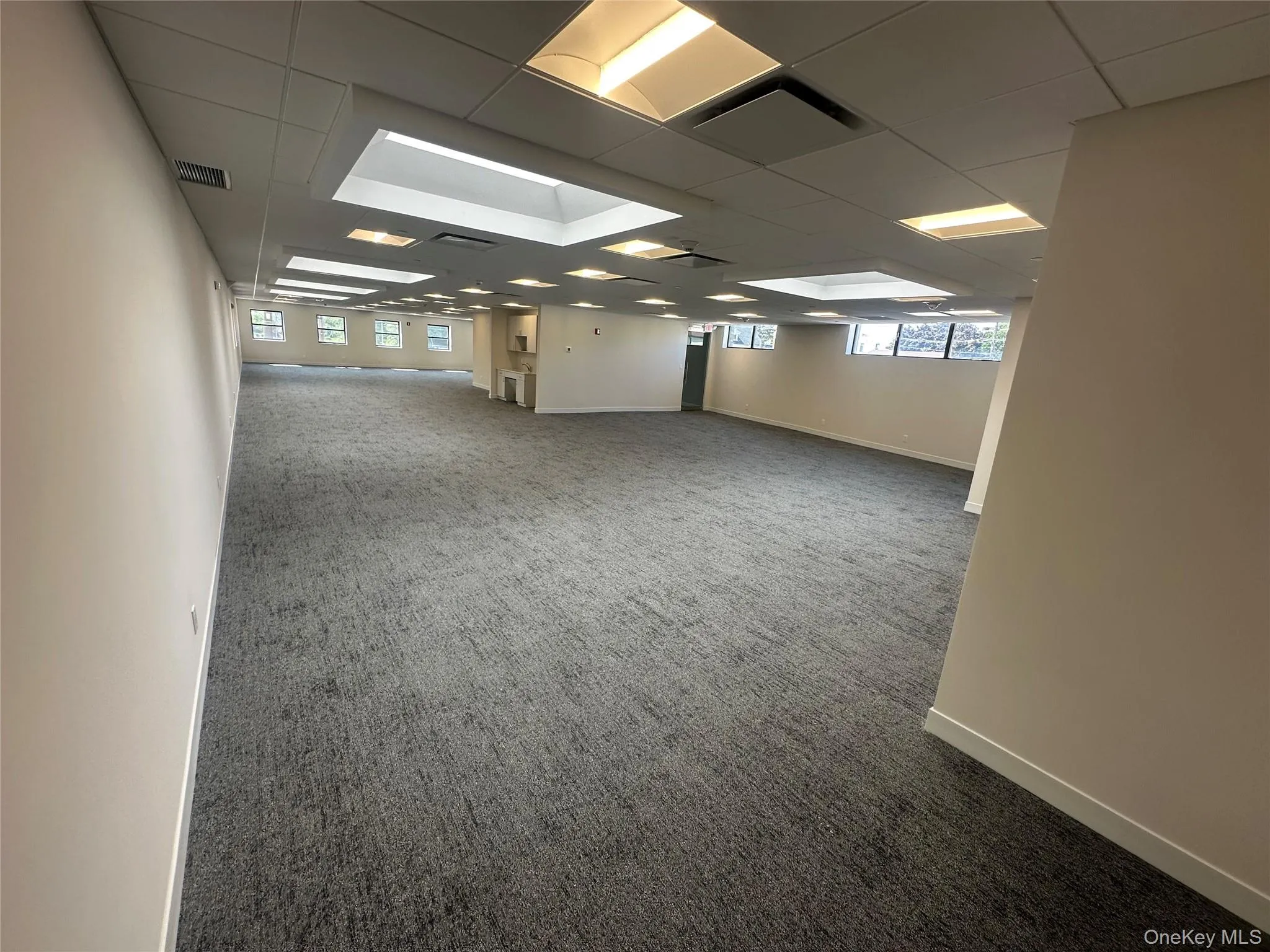 Empty room featuring dark colored carpet and a paneled ceiling Empty room featuring dark colored carpet and a paneled ceiling