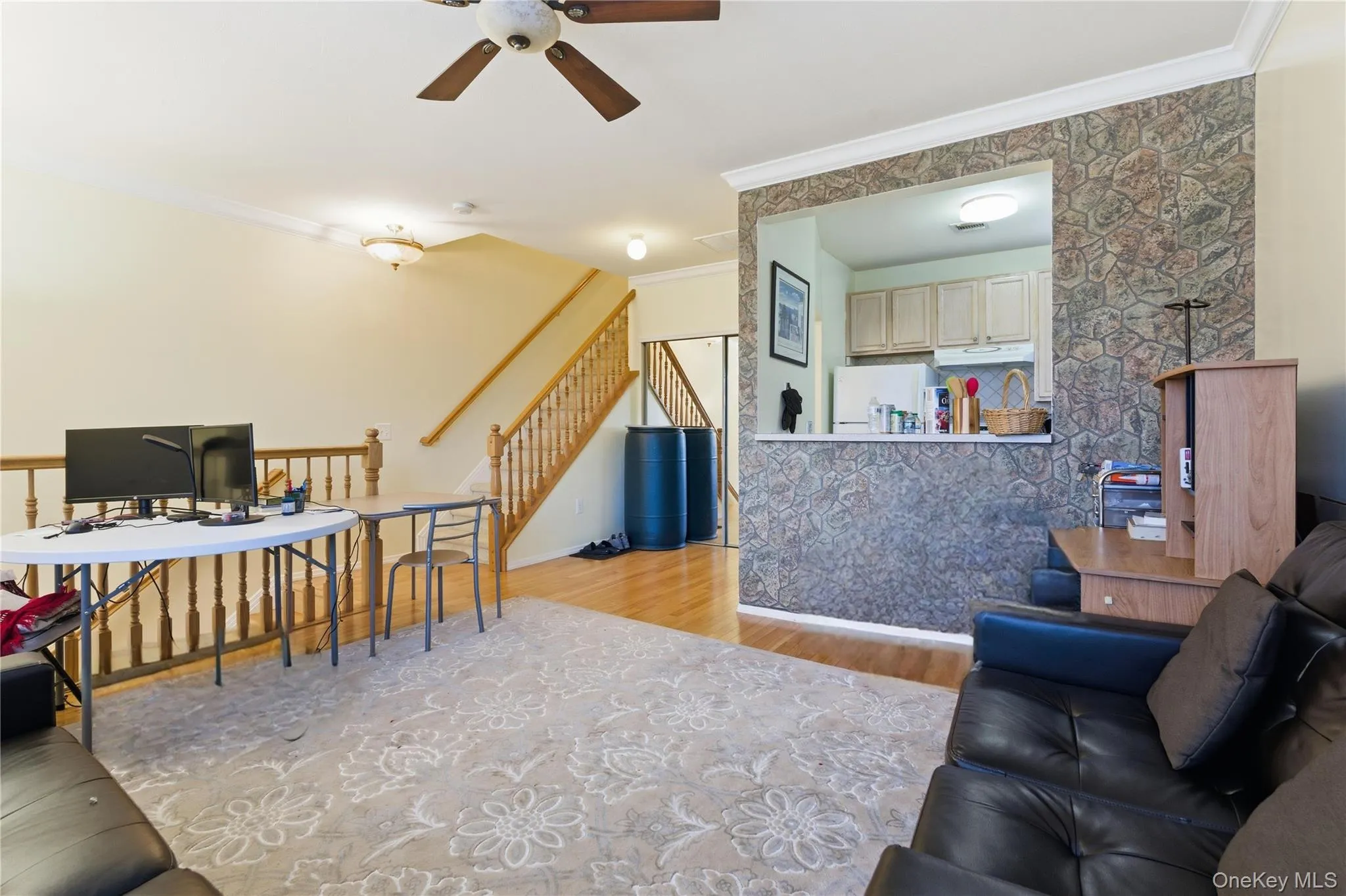 Living room featuring crown molding, light wood-style flooring, ceiling fan, stairway, and an office area Living room featuring crown molding, light wood-style flooring, ceiling fan, stairway, and an office area