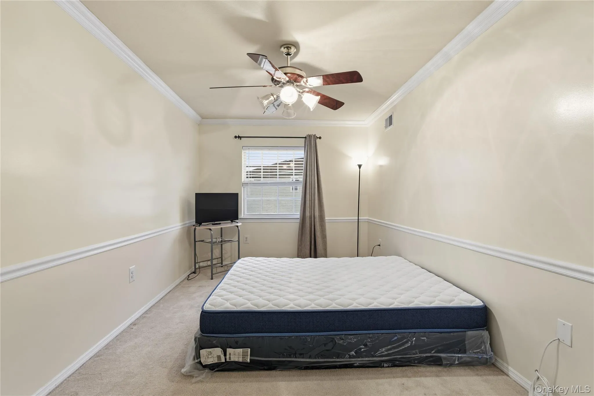 Bedroom featuring light colored carpet, ceiling fan, and ornamental molding Bedroom featuring light colored carpet, ceiling fan, and ornamental molding