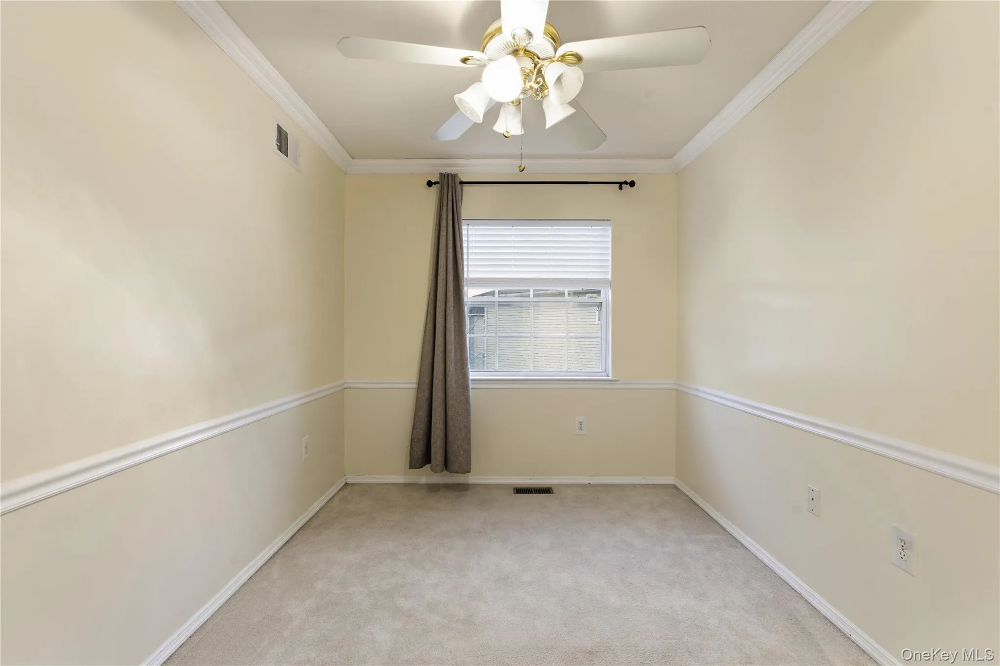 Empty room with light carpet, ornamental molding, and a ceiling fan Empty room with light carpet, ornamental molding, and a ceiling fan