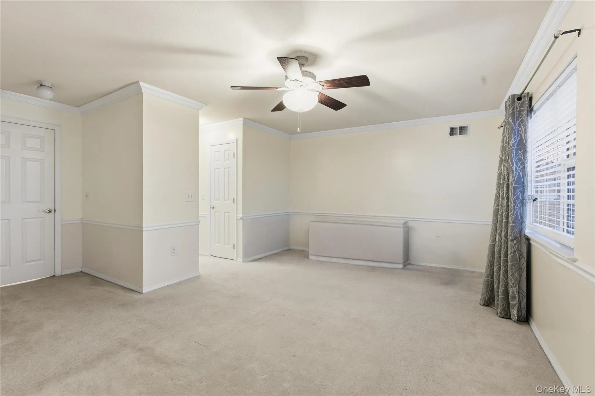 Empty room with light colored carpet, ornamental molding, and a ceiling fan Empty room with light colored carpet, ornamental molding, and a ceiling fan
