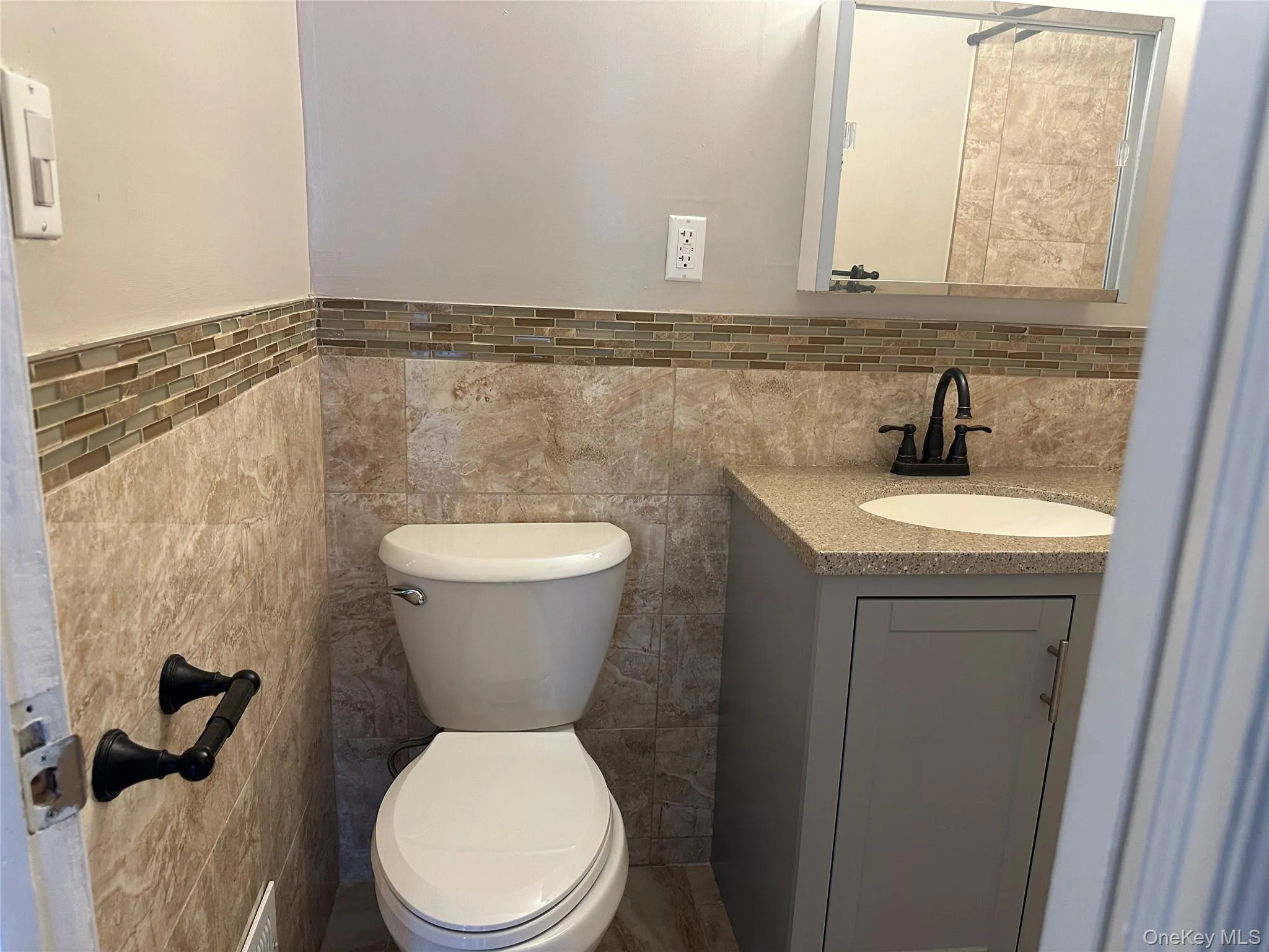 Bathroom featuring vanity, tile walls, and wainscoting Bathroom featuring vanity, tile walls, and wainscoting