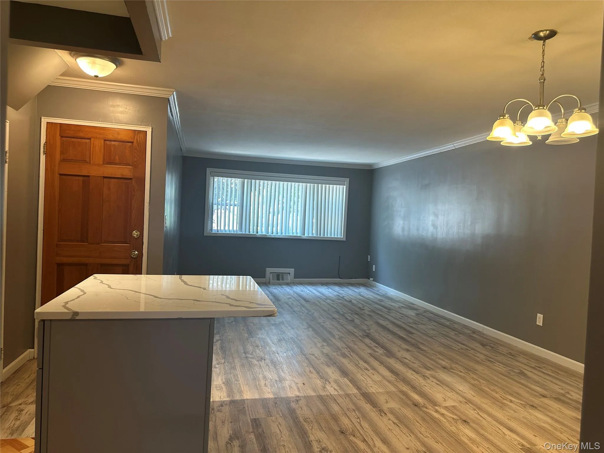 Living area with ornamental molding, wood finished floors, and a chandelier Living area with ornamental molding, wood finished floors, and a chandelier