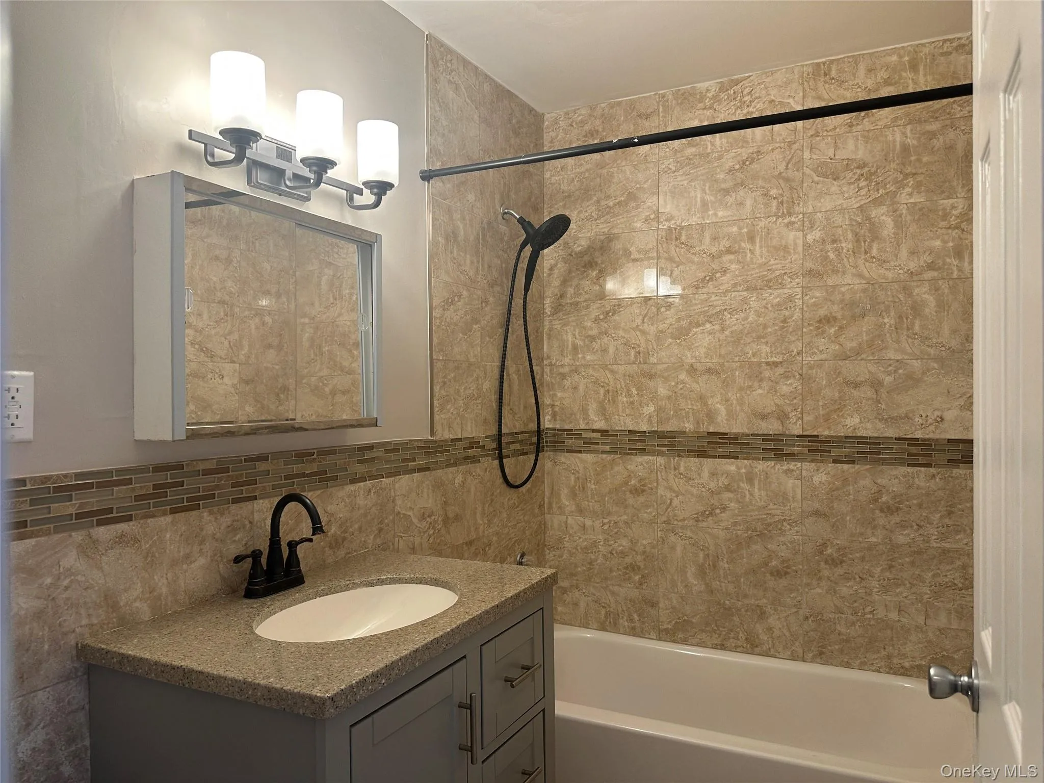 Full bath featuring shower / tub combination, vanity, tile walls, and decorative backsplash Full bath featuring shower / tub combination, vanity, tile walls, and decorative backsplash