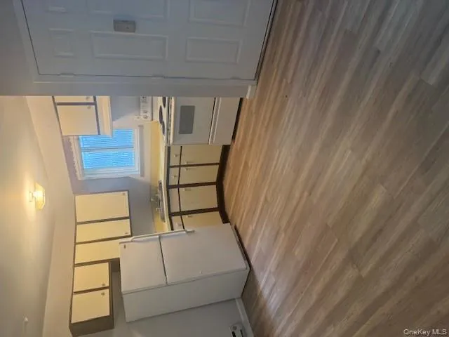 Kitchen featuring white cabinetry, fridge, range, light wood finished floors, and light countertops Kitchen featuring white cabinetry, fridge, range, light wood finished floors, and light countertops