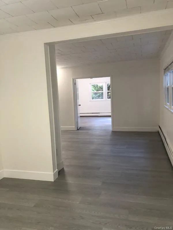 Hallway with a baseboard heating unit and dark wood-type flooring Hallway with a baseboard heating unit and dark wood-type flooring