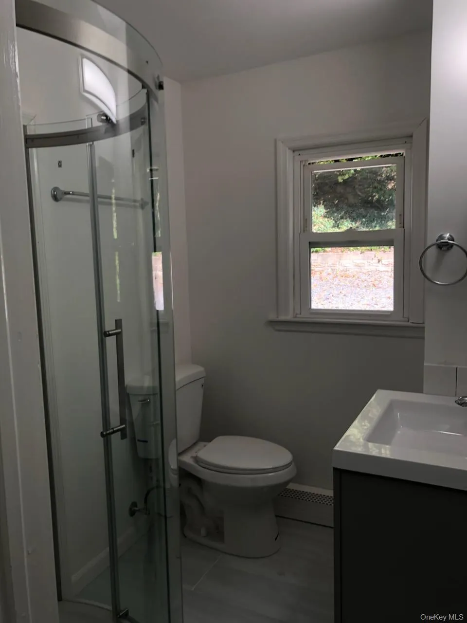 Bathroom with vanity, a shower stall, and a baseboard heating unit Bathroom with vanity, a shower stall, and a baseboard heating unit