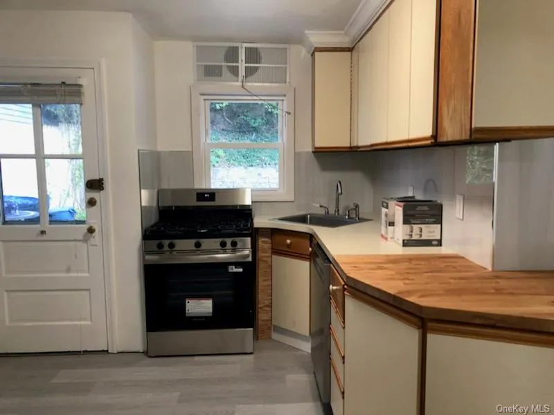 Kitchen with appliances with stainless steel finishes, light wood finished floors, cream cabinetry, and tasteful backsplash Kitchen with appliances with stainless steel finishes, light wood finished floors, cream cabinetry, and tasteful backsplash