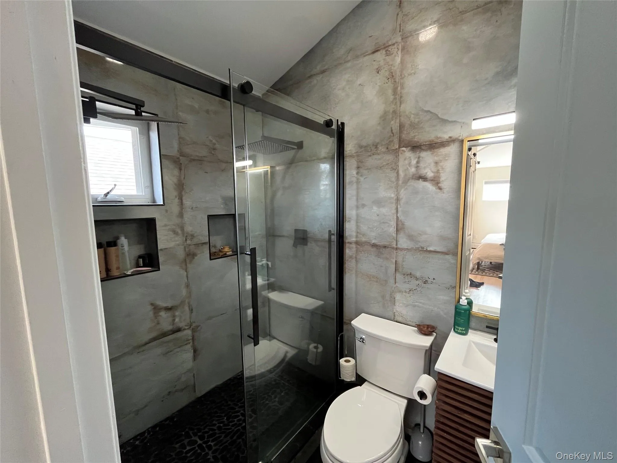 Full bathroom with vanity, a stall shower, vaulted ceiling, ensuite bath, and tile walls Full bathroom with vanity, a stall shower, vaulted ceiling, ensuite bath, and tile walls