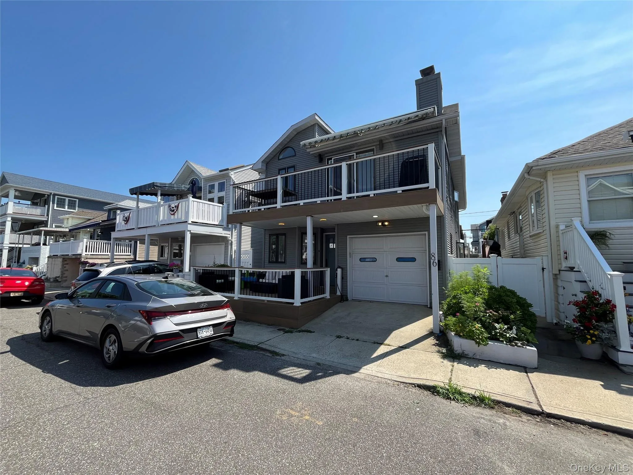 View of front facade with an attached garage, a chimney, a balcony, and driveway View of front facade with an attached garage, a chimney, a balcony, and driveway
