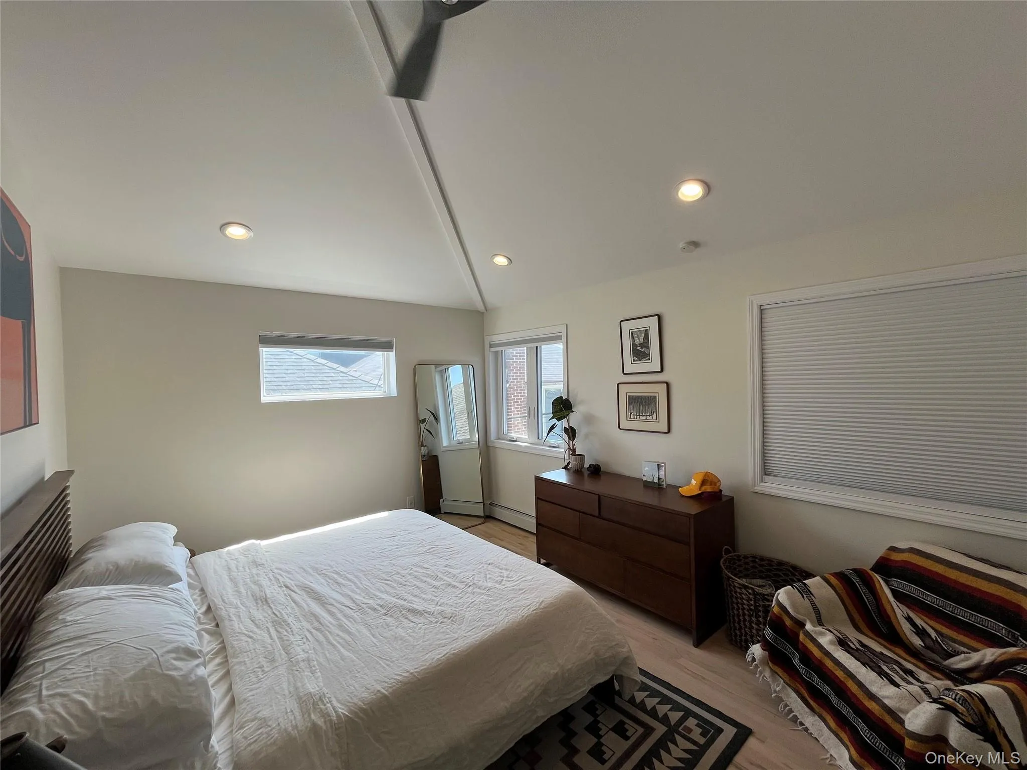 Bedroom featuring light wood-style floors, recessed lighting, a baseboard heating unit, and lofted ceiling Bedroom featuring light wood-style floors, recessed lighting, a baseboard heating unit, and lofted ceiling