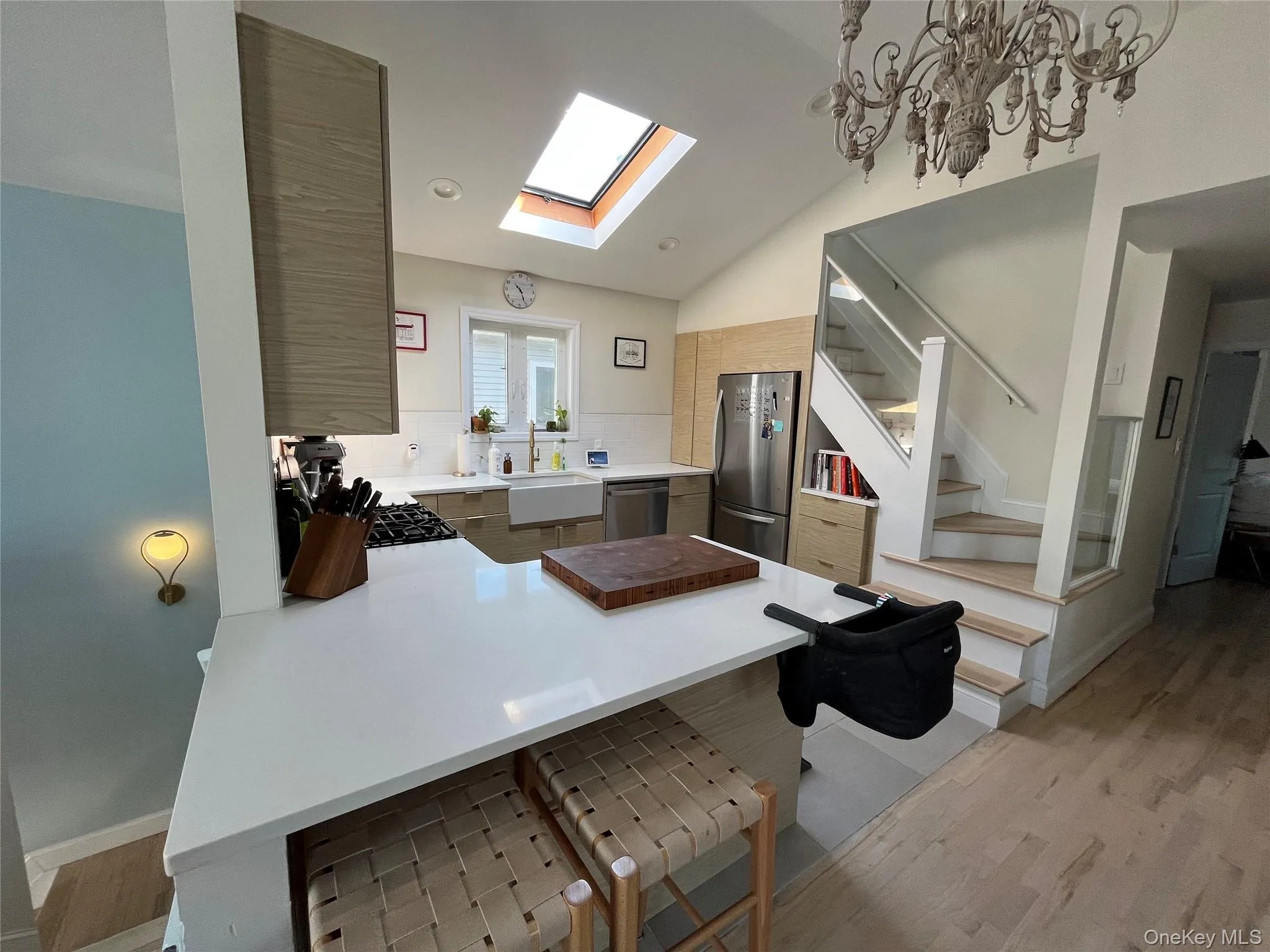 Kitchen with a peninsula, vaulted ceiling, a skylight, stainless steel appliances, and light wood-type flooring Kitchen with a peninsula, vaulted ceiling, a skylight, stainless steel appliances, and light wood-type flooring