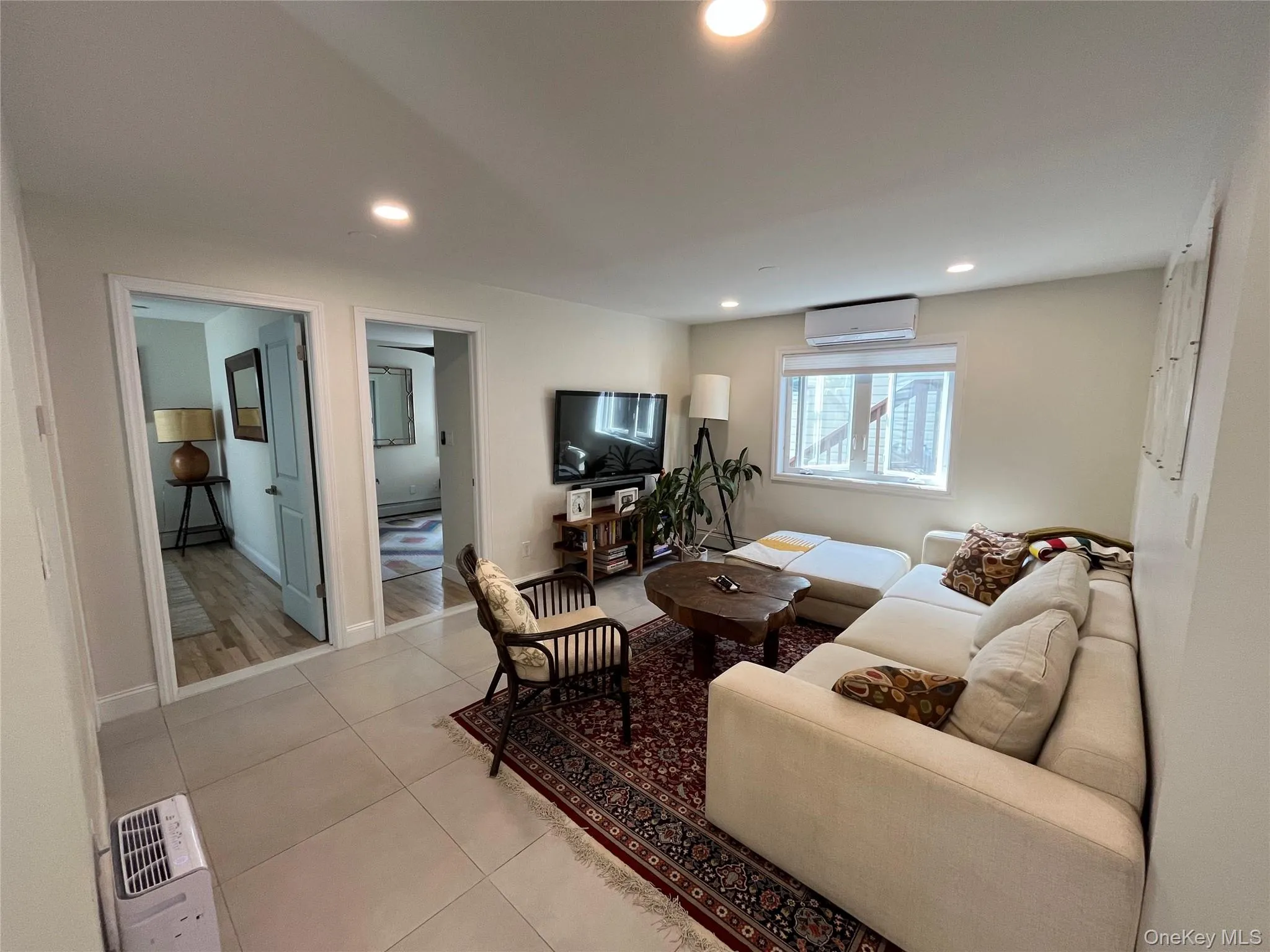 Living room with light tile patterned floors, recessed lighting, and an AC wall unit Living room with light tile patterned floors, recessed lighting, and an AC wall unit
