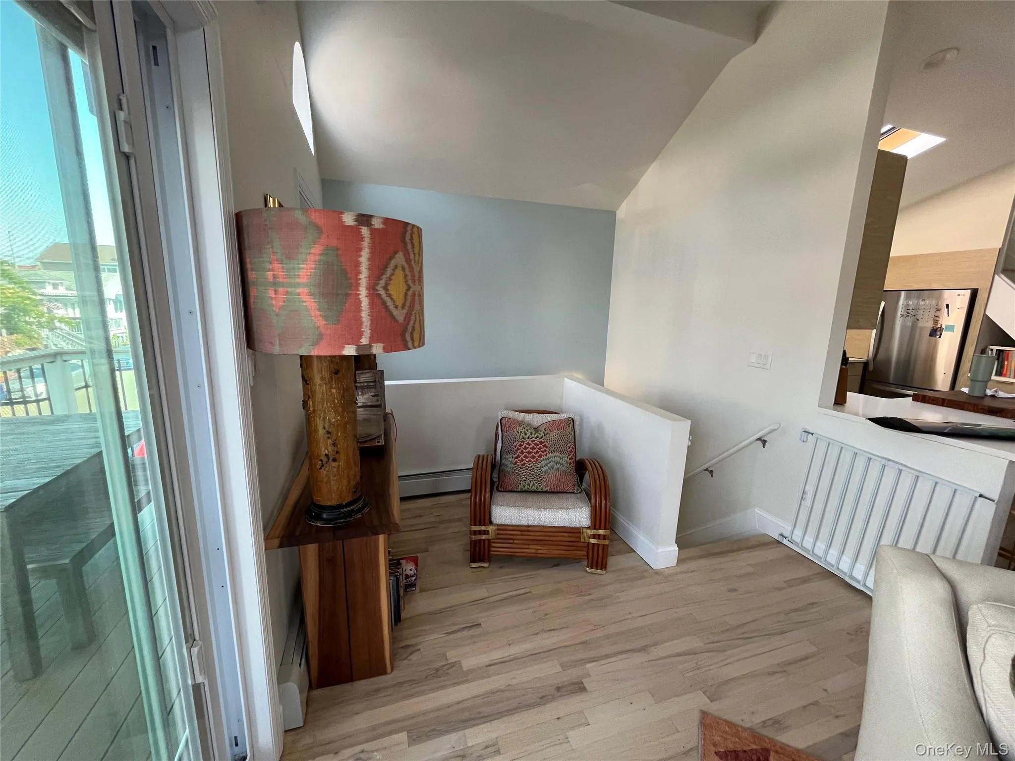 Sitting room with an upstairs landing, light wood-style floors, vaulted ceiling, and a baseboard heating unit Sitting room with an upstairs landing, light wood-style floors, vaulted ceiling, and a baseboard heating unit