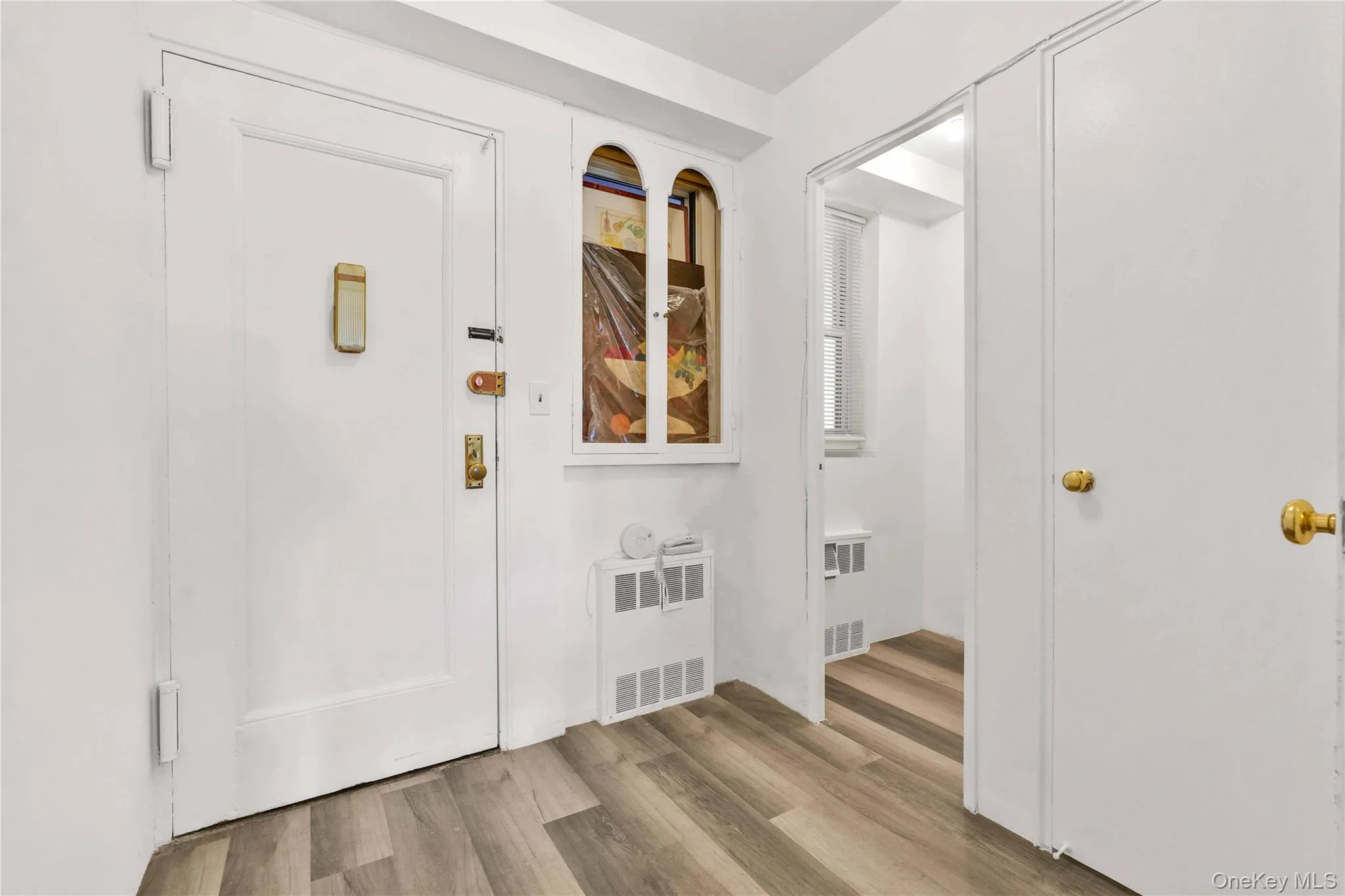 Foyer with light wood finished floors, stairs, and radiator Foyer with light wood finished floors, stairs, and radiator