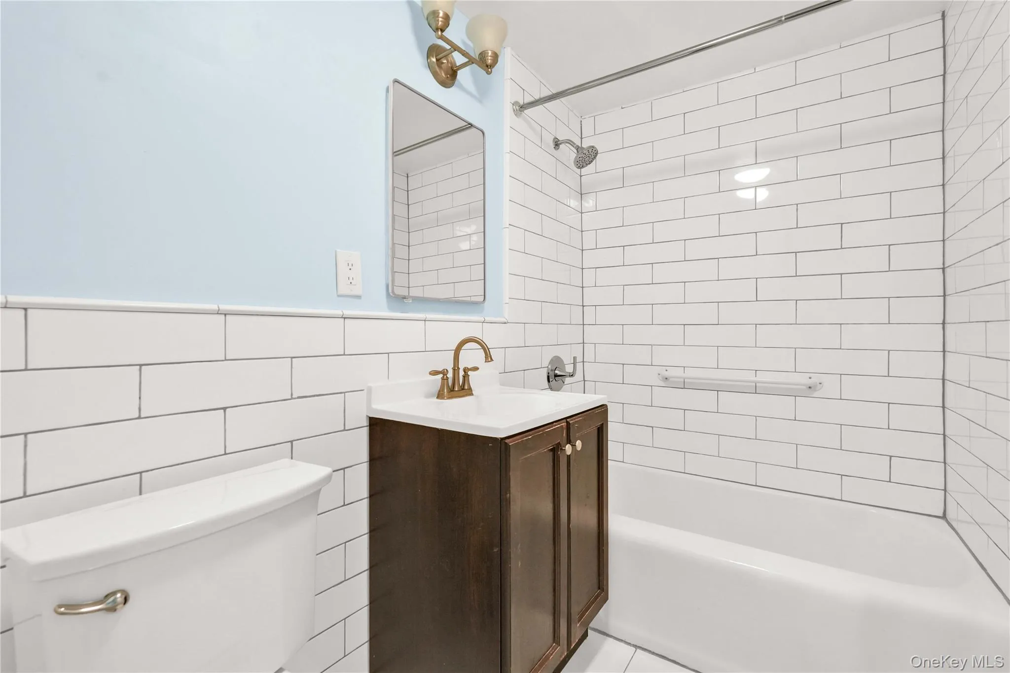 Bathroom featuring shower combination, tile walls, and vanity Bathroom featuring shower combination, tile walls, and vanity