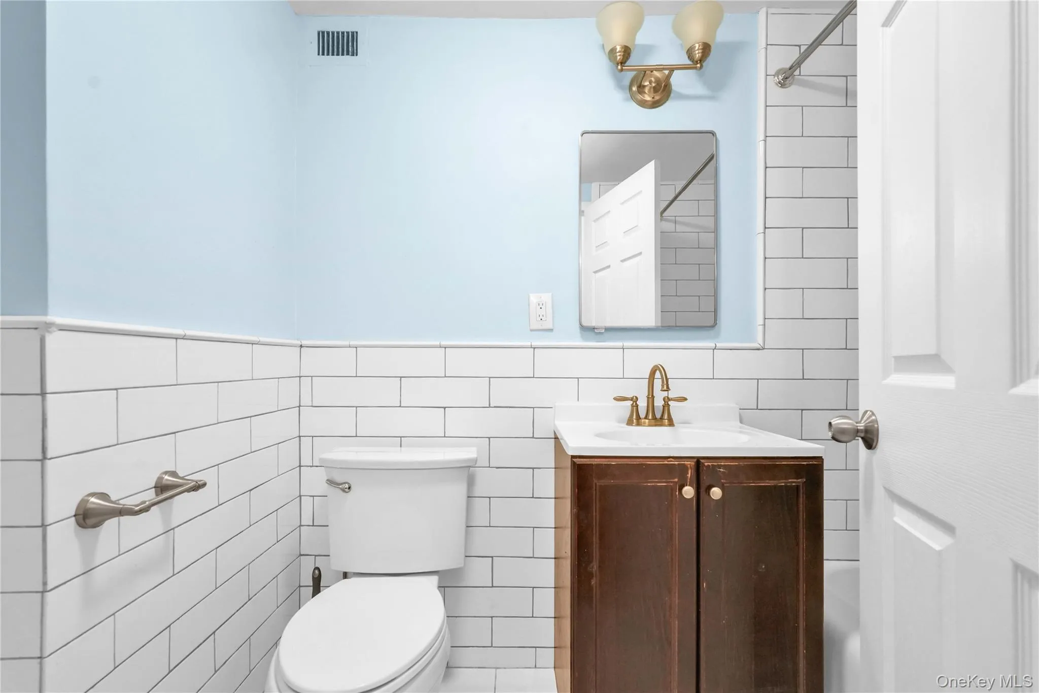 Full bath featuring tile walls, vanity, wainscoting, and a shower Full bath featuring tile walls, vanity, wainscoting, and a shower