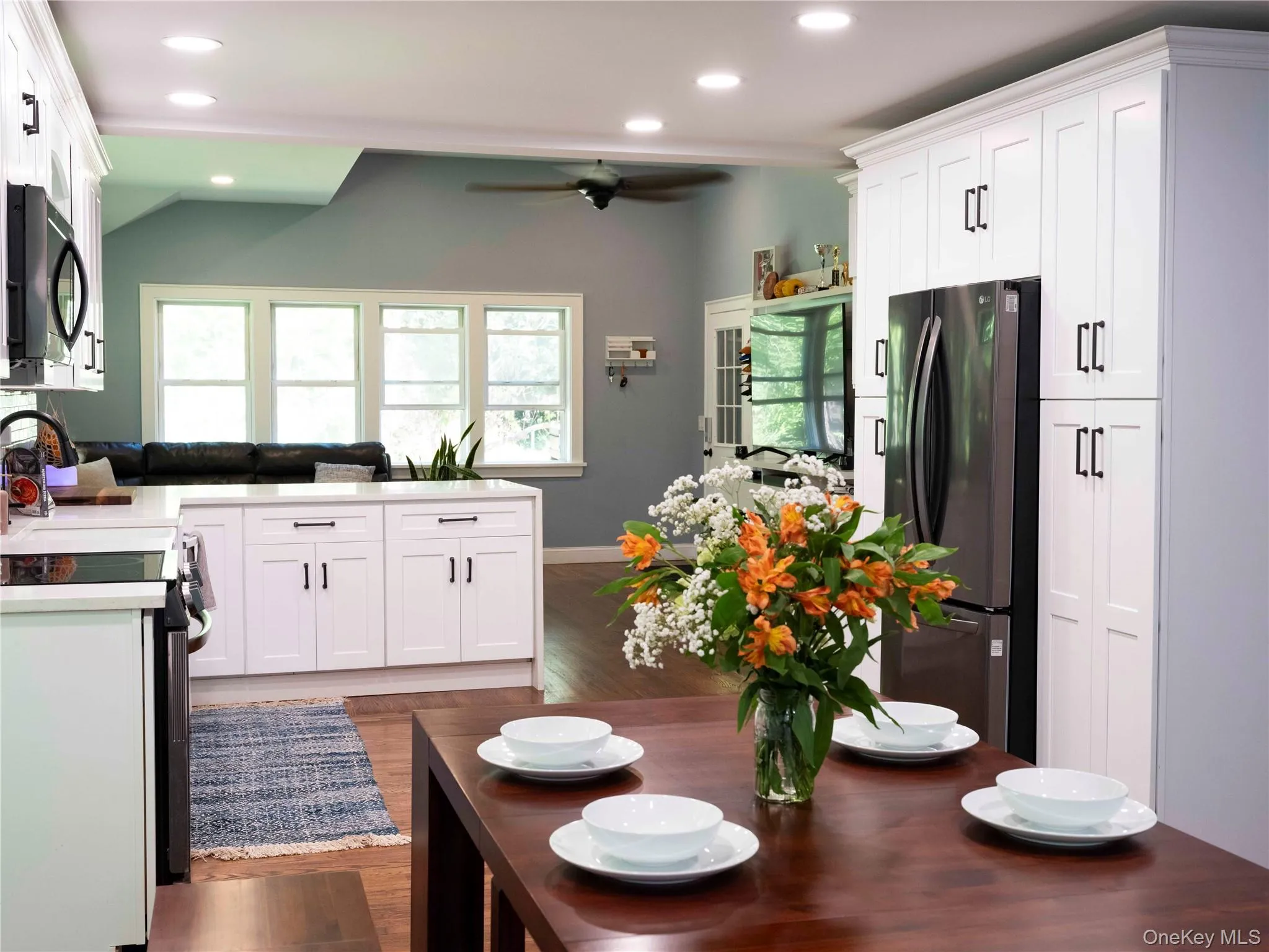 Kitchen with white cabinets, freestanding refrigerator, recessed lighting, dark wood-style flooring, and vaulted ceiling Kitchen with white cabinets, freestanding refrigerator, recessed lighting, dark wood-style flooring, and vaulted ceiling