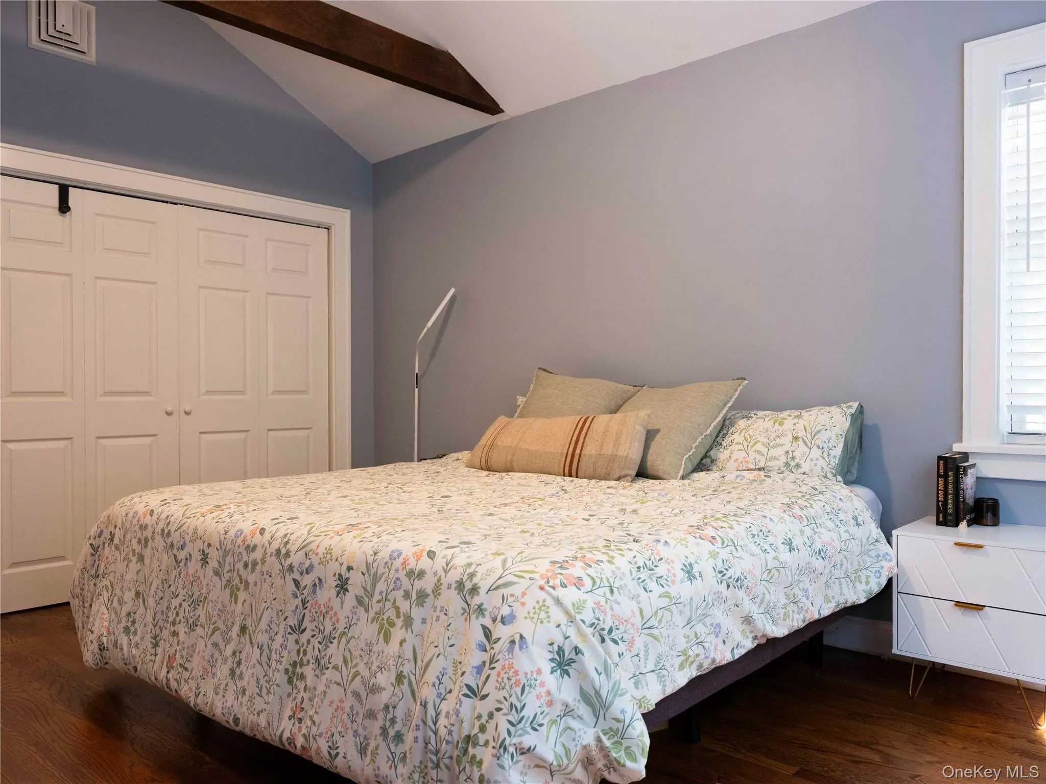 Bedroom with dark wood-style floors, a closet, and multiple windows Bedroom with dark wood-style floors, a closet, and multiple windows