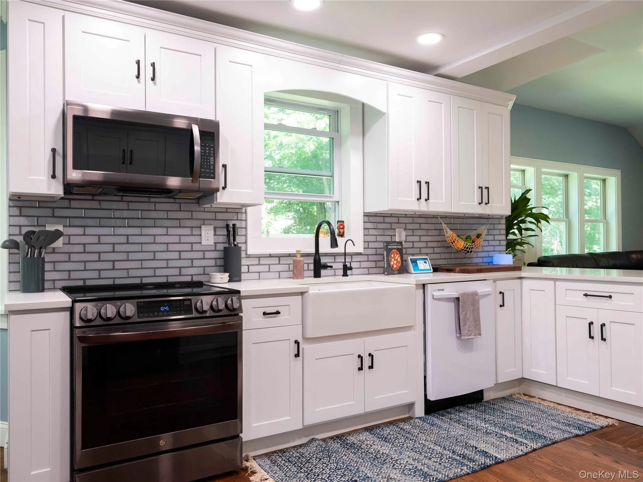 Kitchen featuring stainless steel appliances, white cabinetry, backsplash, dark wood-style floors, and recessed lighting Kitchen featuring stainless steel appliances, white cabinetry, backsplash, dark wood-style floors, and recessed lighting