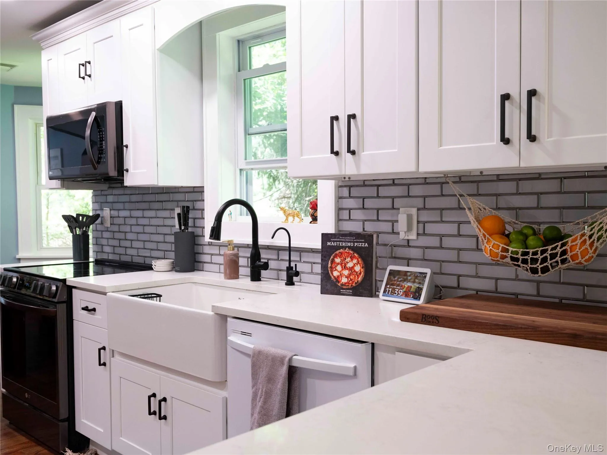 Kitchen with black range with electric cooktop, backsplash, white cabinetry, and dishwashing machine Kitchen with black range with electric cooktop, backsplash, white cabinetry, and dishwashing machine