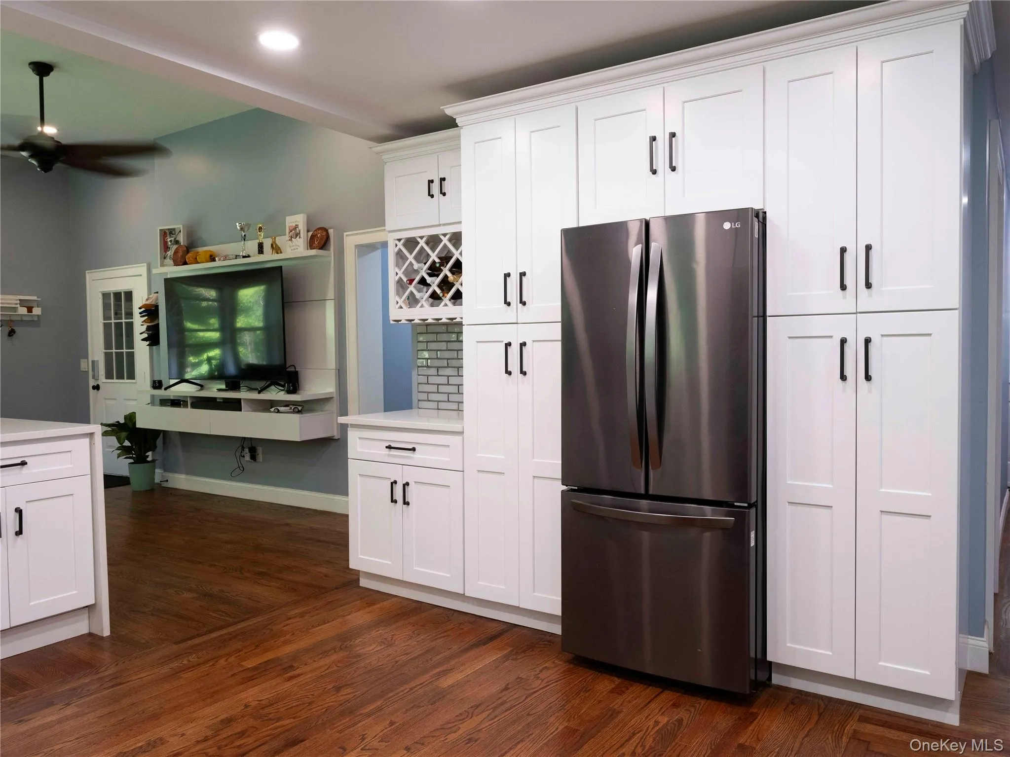 Kitchen featuring freestanding refrigerator, white cabinetry, dark wood-style flooring, a ceiling fan, and recessed lighting Kitchen featuring freestanding refrigerator, white cabinetry, dark wood-style flooring, a ceiling fan, and recessed lighting