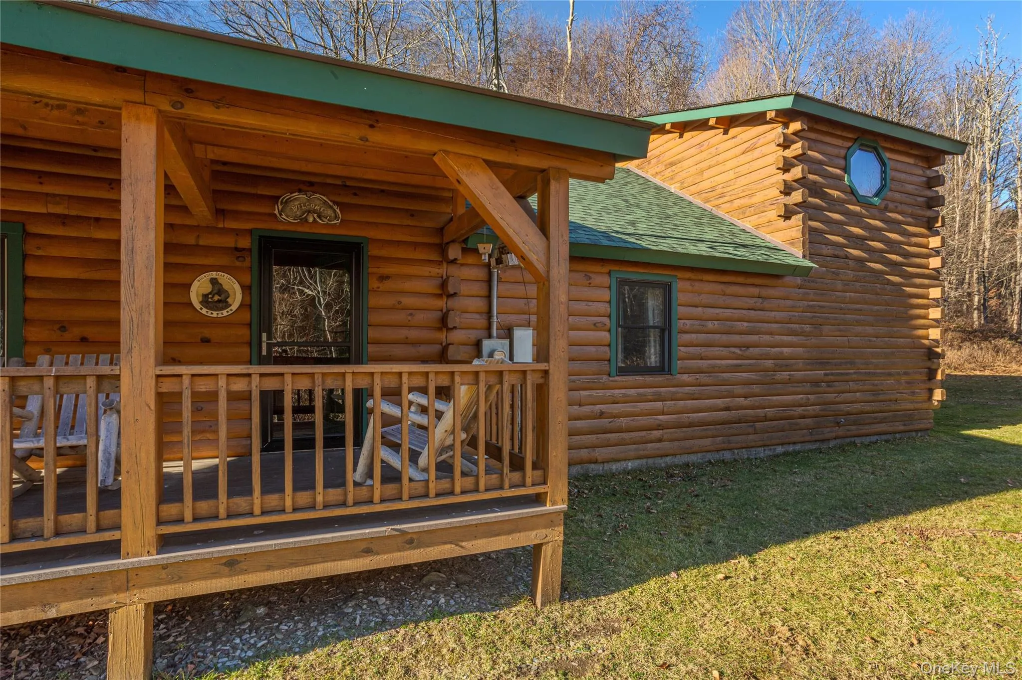 View of side of property featuring a shingled roof, log siding, a wooden deck, and a lawn View of side of property featuring a shingled roof, log siding, a wooden deck, and a lawn