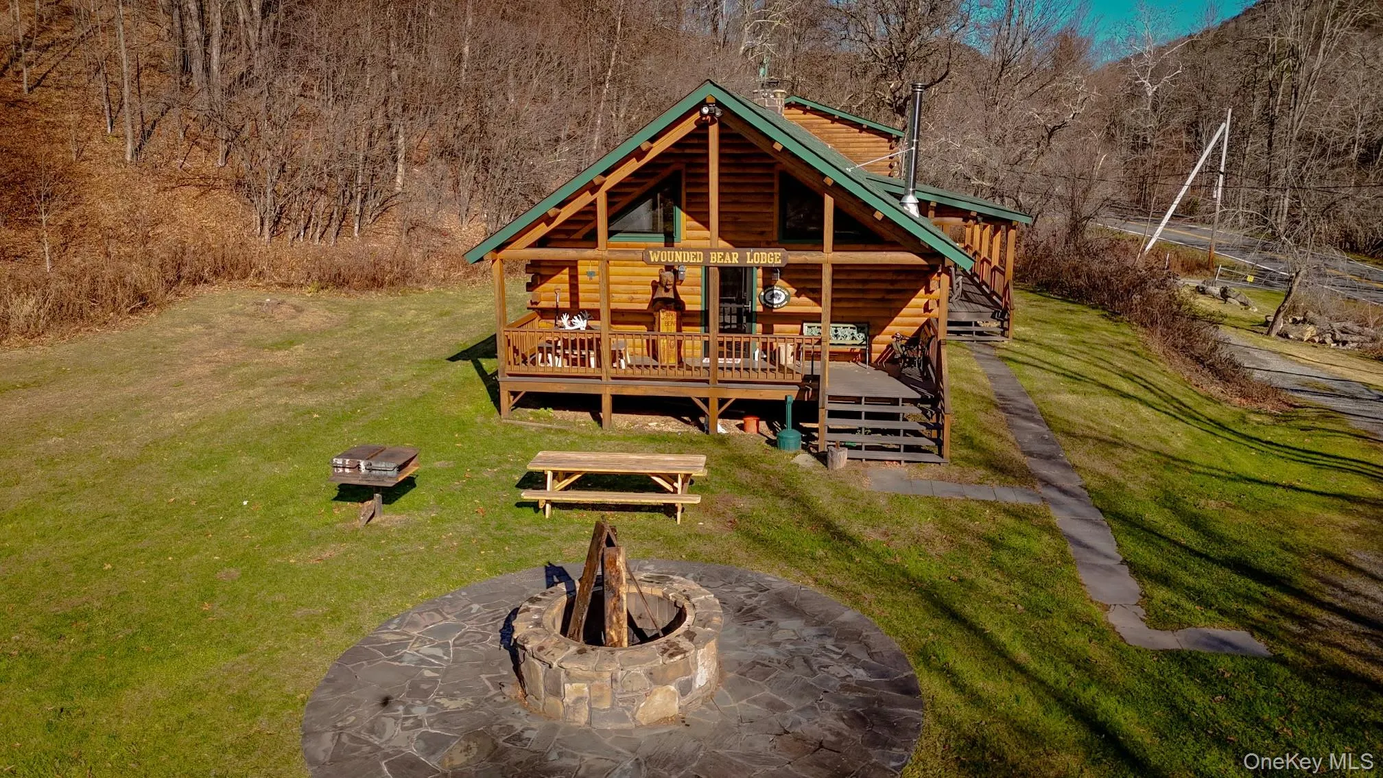 Back of property featuring an outdoor fire pit, a wooden deck, log veneer siding, and a yard Back of property featuring an outdoor fire pit, a wooden deck, log veneer siding, and a yard