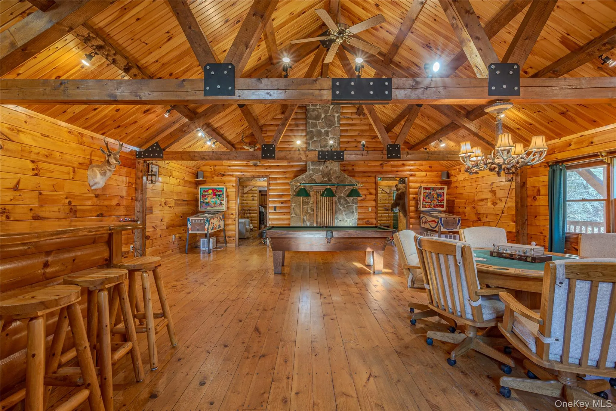 Recreation room featuring hardwood / wood-style flooring, a wooden ceiling with exposed beams, wooden walls, high vaulted ceiling, and a ceiling fan Recreation room featuring hardwood / wood-style flooring, a wooden ceiling with exposed beams, wooden walls, high vaulted ceiling, and a ceiling fan