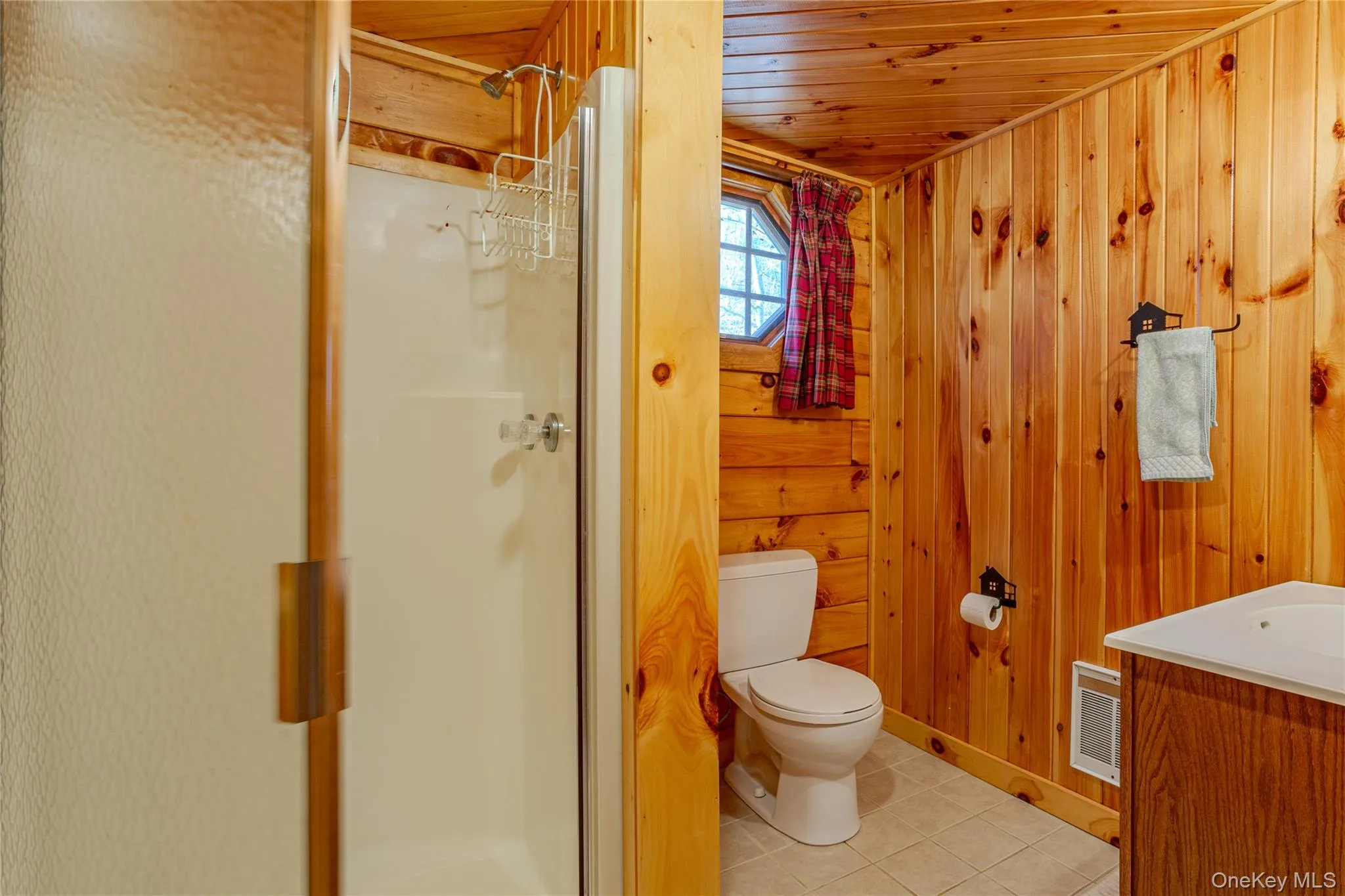 Full bathroom with a stall shower, vanity, light tile patterned floors, wood walls, and wooden ceiling Full bathroom with a stall shower, vanity, light tile patterned floors, wood walls, and wooden ceiling