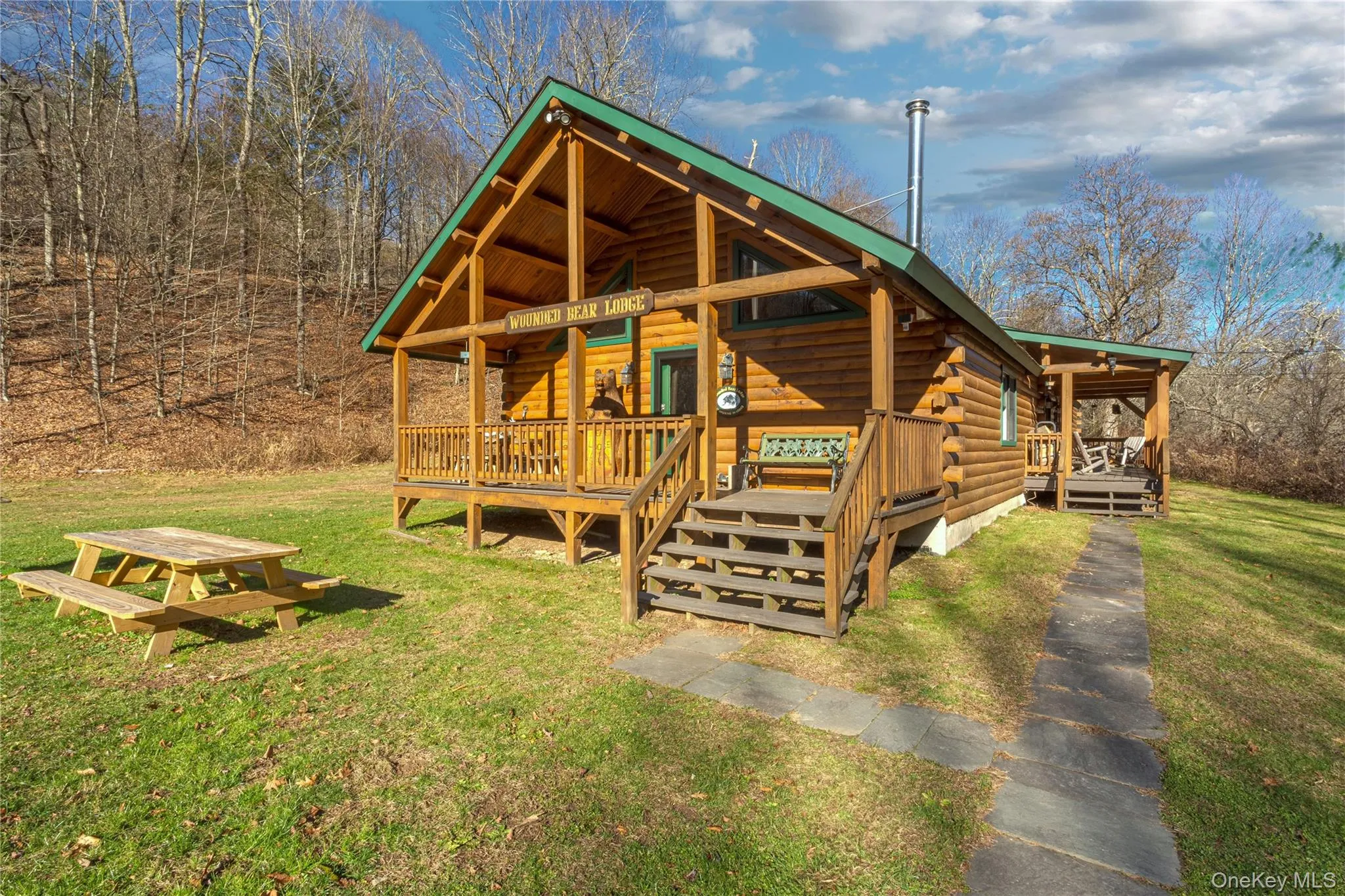 View of front facade with log siding, a front yard, and a deck View of front facade with log siding, a front yard, and a deck