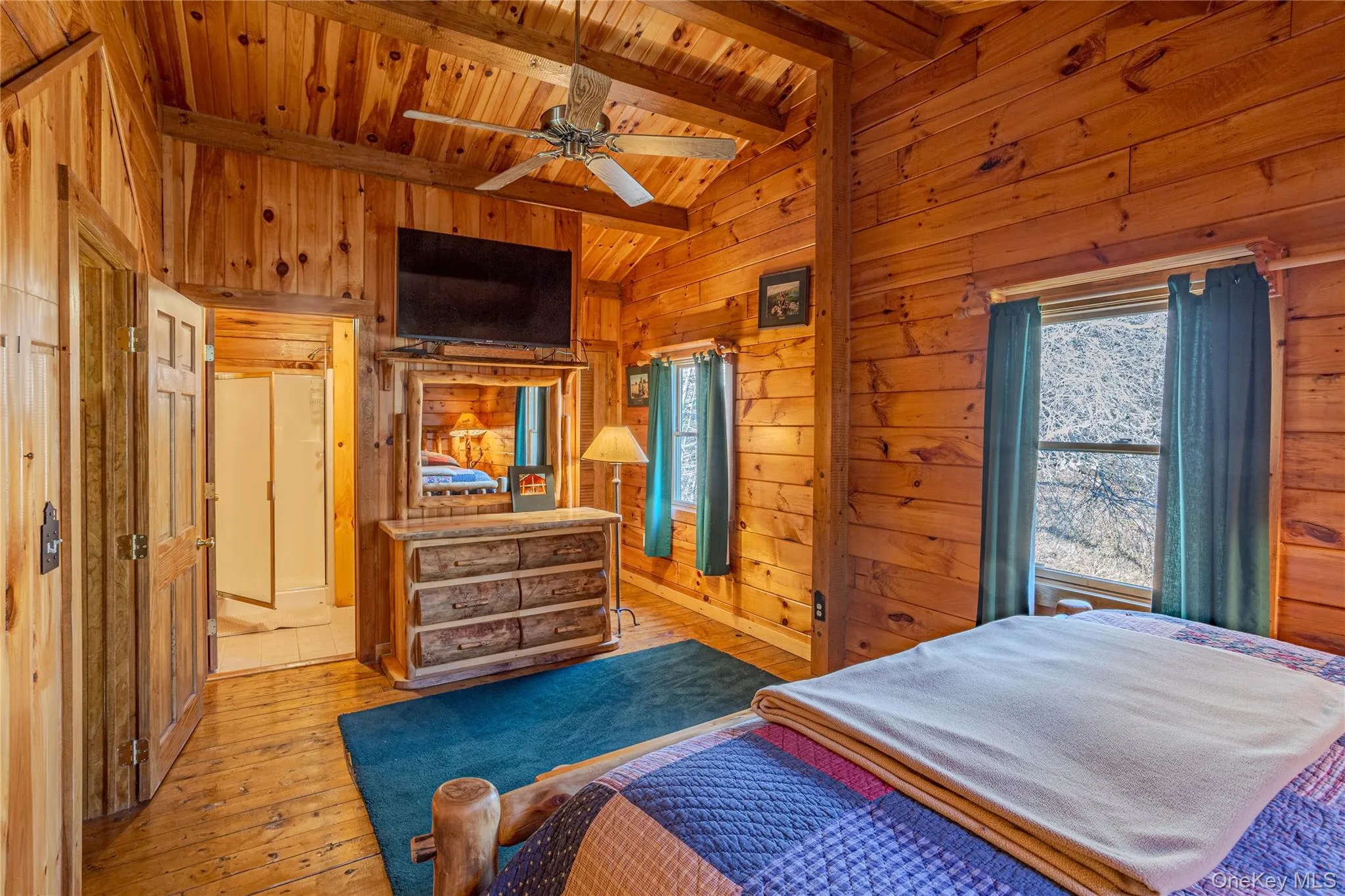 Bedroom featuring hardwood / wood-style floors, wood walls, wood ceiling, and a ceiling fan Bedroom featuring hardwood / wood-style floors, wood walls, wood ceiling, and a ceiling fan