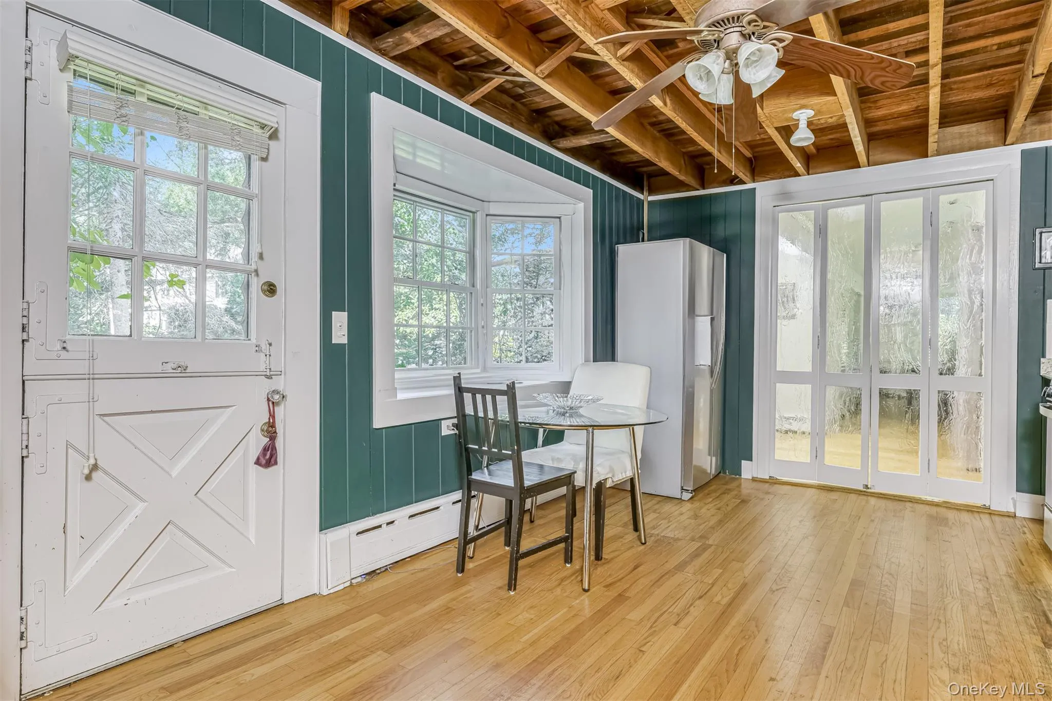 Dining space featuring wooden ceiling, wood-type flooring, ceiling fan, and wooden walls Dining space featuring wooden ceiling, wood-type flooring, ceiling fan, and wooden walls