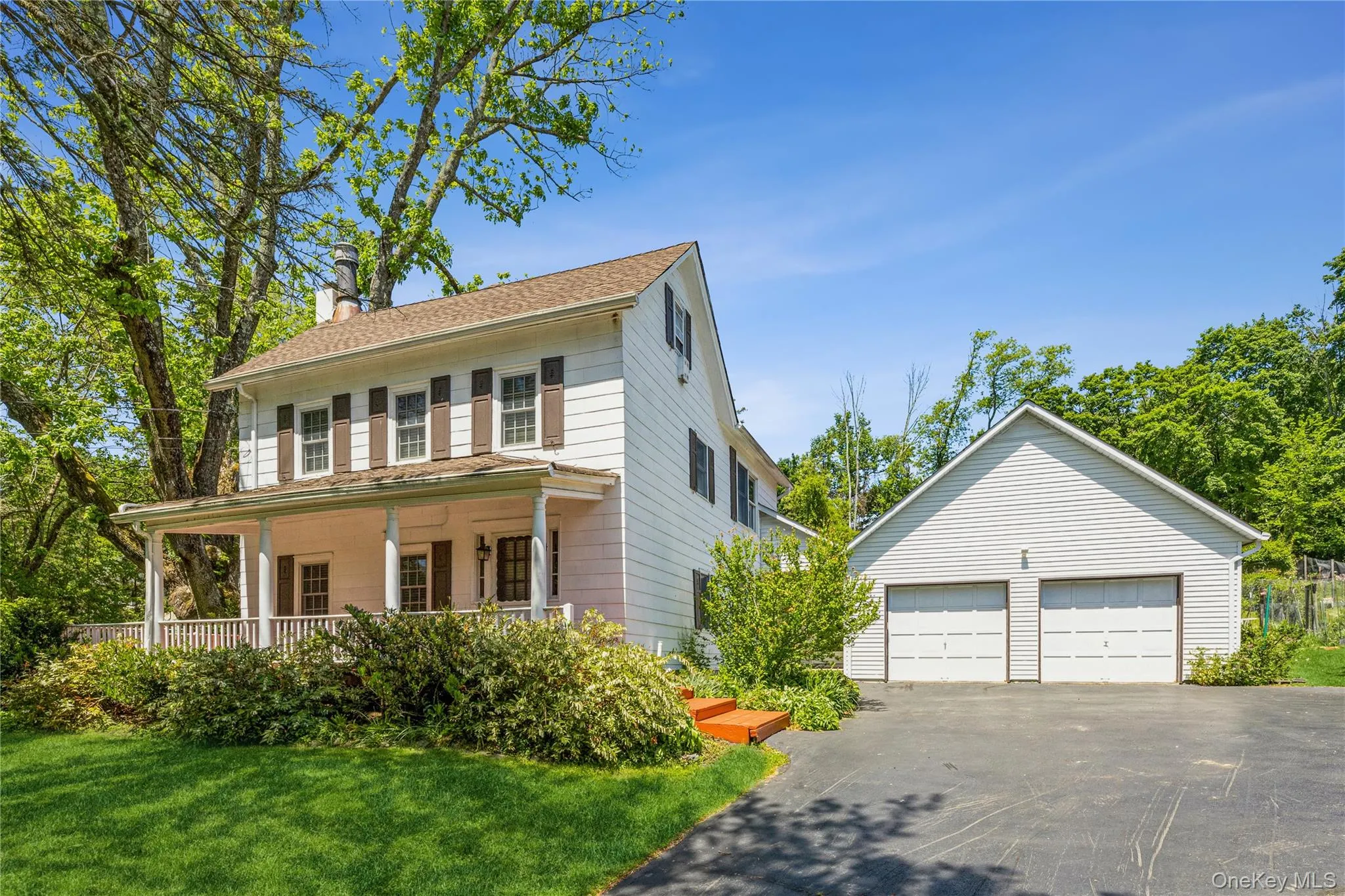 Colonial house featuring an outdoor structure, a garage, a chimney, covered porch, and a front lawn Colonial house featuring an outdoor structure, a garage, a chimney, covered porch, and a front lawn