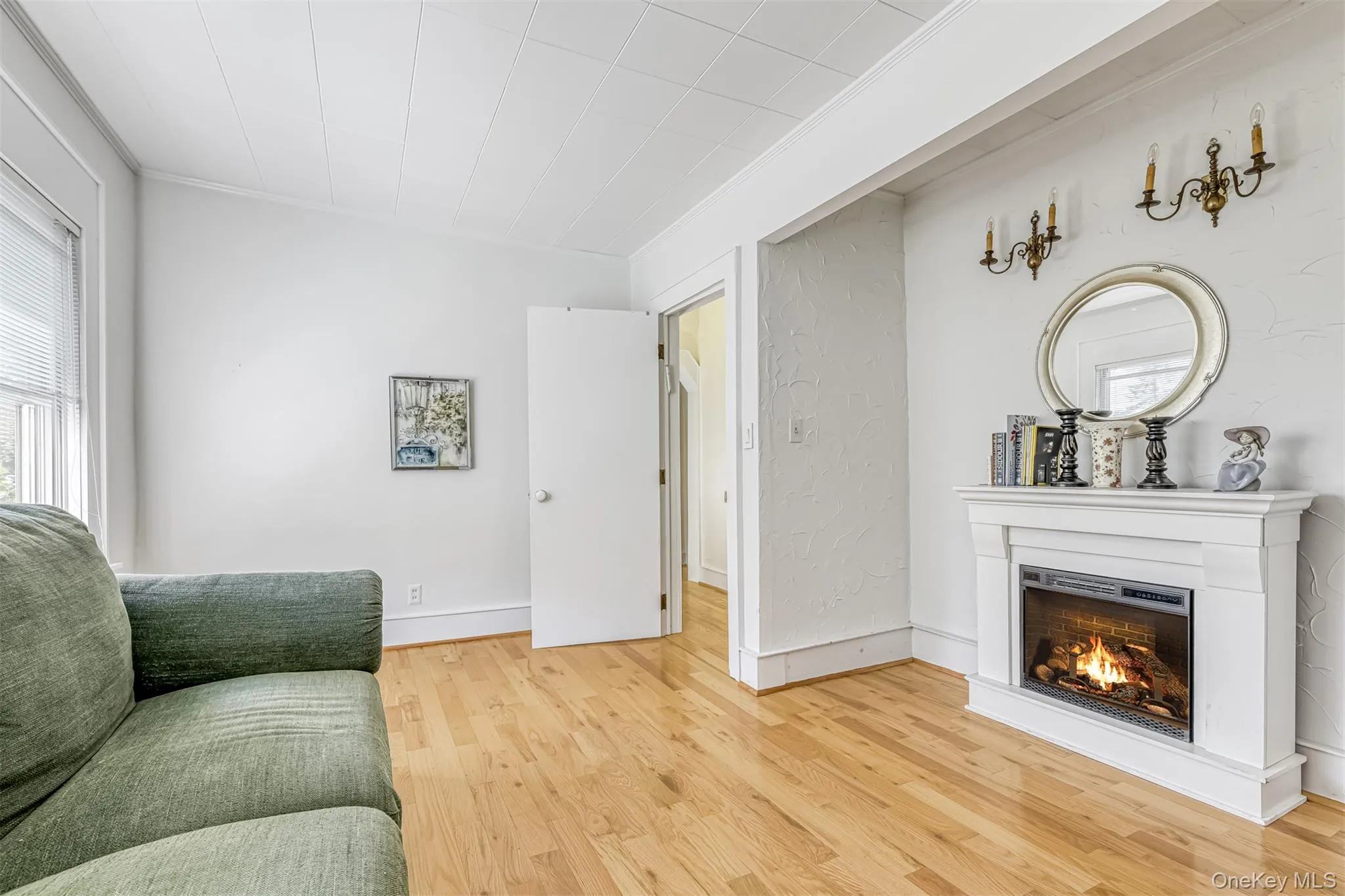 Living room with light wood-style floors, crown molding, and a warm lit fireplace Living room with light wood-style floors, crown molding, and a warm lit fireplace