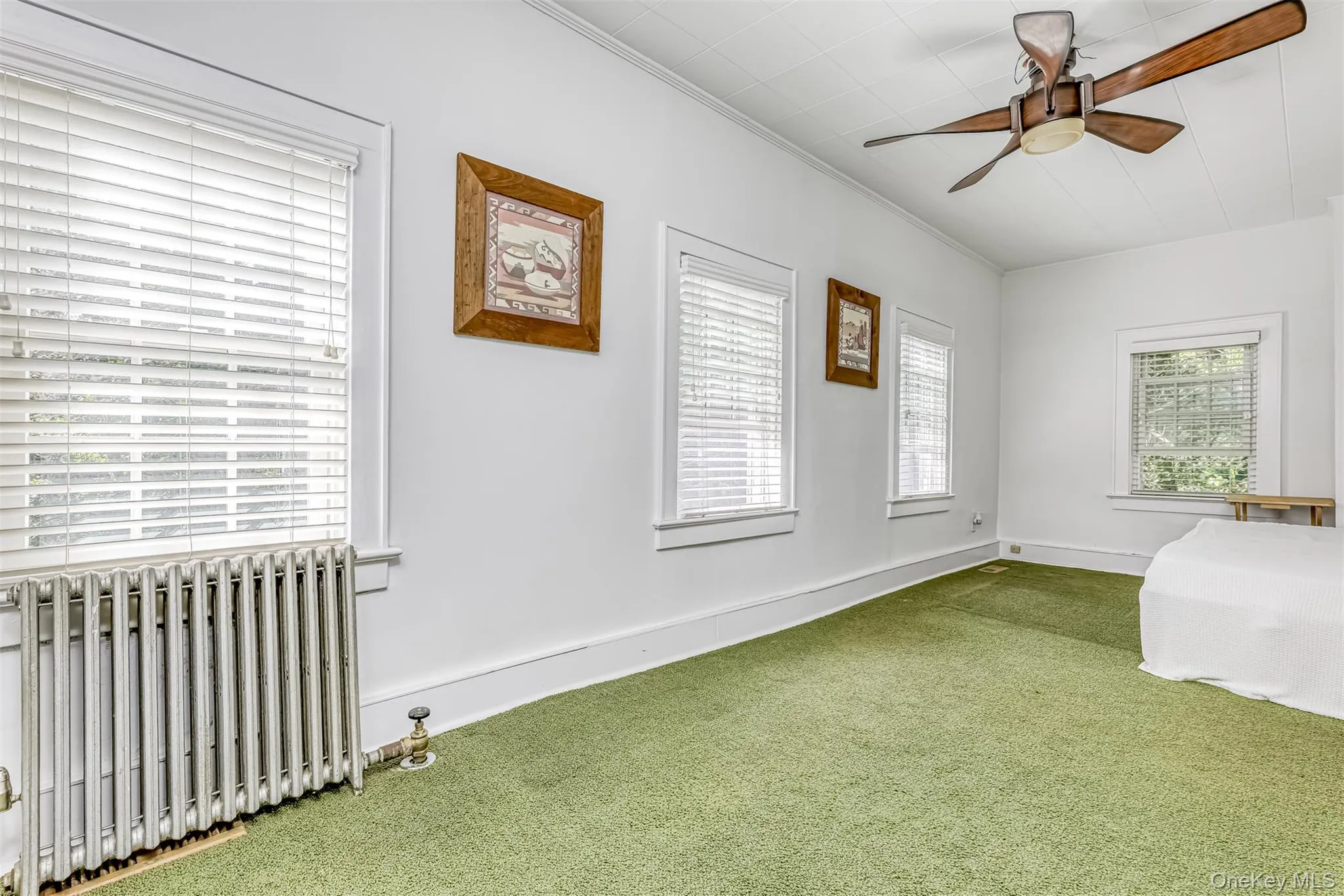 Unfurnished bedroom featuring radiator heating unit, carpet floors, ornamental molding, and ceiling fan Unfurnished bedroom featuring radiator heating unit, carpet floors, ornamental molding, and ceiling fan