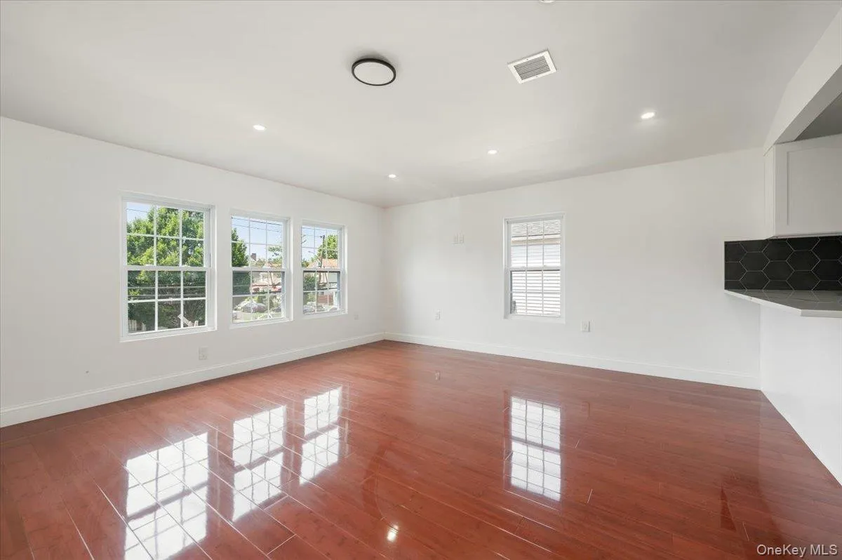 Empty room featuring plenty of natural light, dark wood-type flooring, and recessed lighting Empty room featuring plenty of natural light, dark wood-type flooring, and recessed lighting