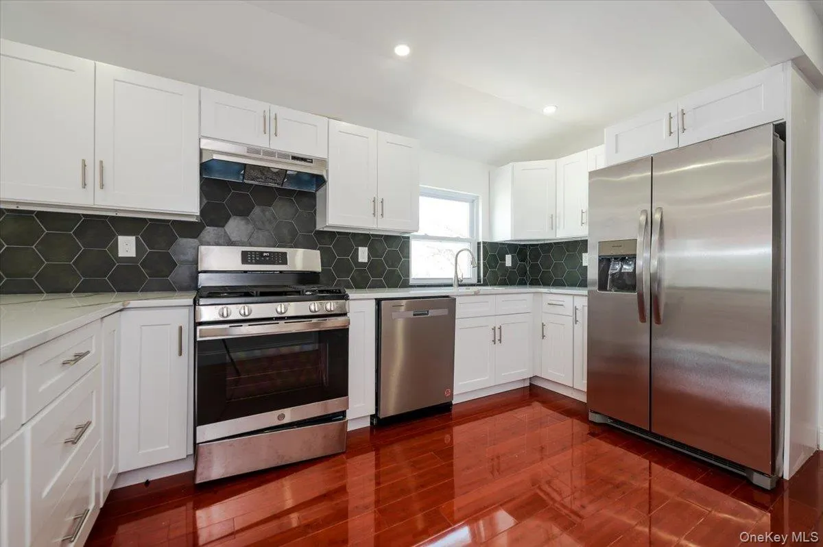 Kitchen with white cabinetry, stainless steel appliances, decorative backsplash, under cabinet range hood, and recessed lighting Kitchen with white cabinetry, stainless steel appliances, decorative backsplash, under cabinet range hood, and recessed lighting