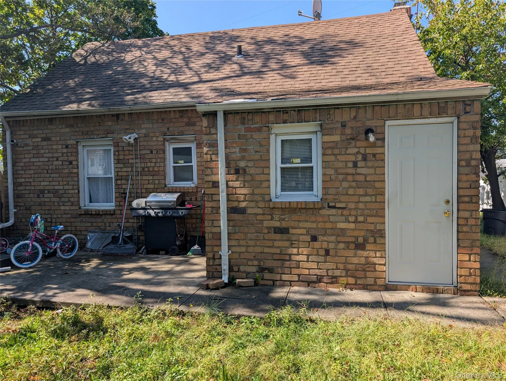 Rear view of house with roof with shingles, stone siding, and a patio area Rear view of house with roof with shingles, stone siding, and a patio area