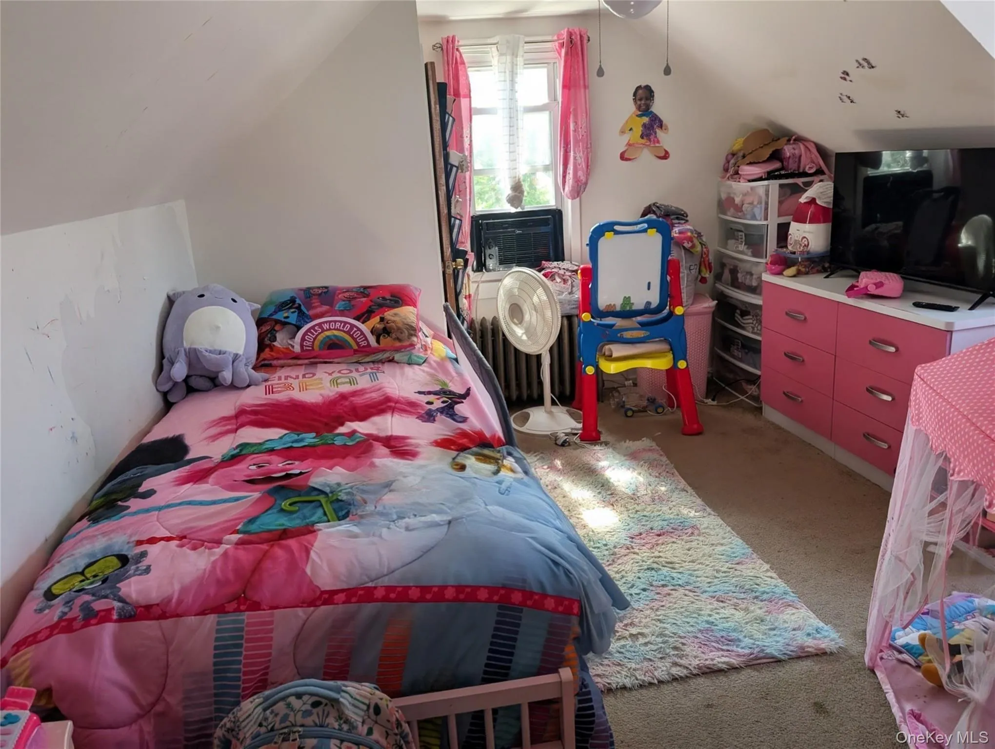 Bedroom featuring vaulted ceiling, light carpet, a ceiling fan, and radiator Bedroom featuring vaulted ceiling, light carpet, a ceiling fan, and radiator