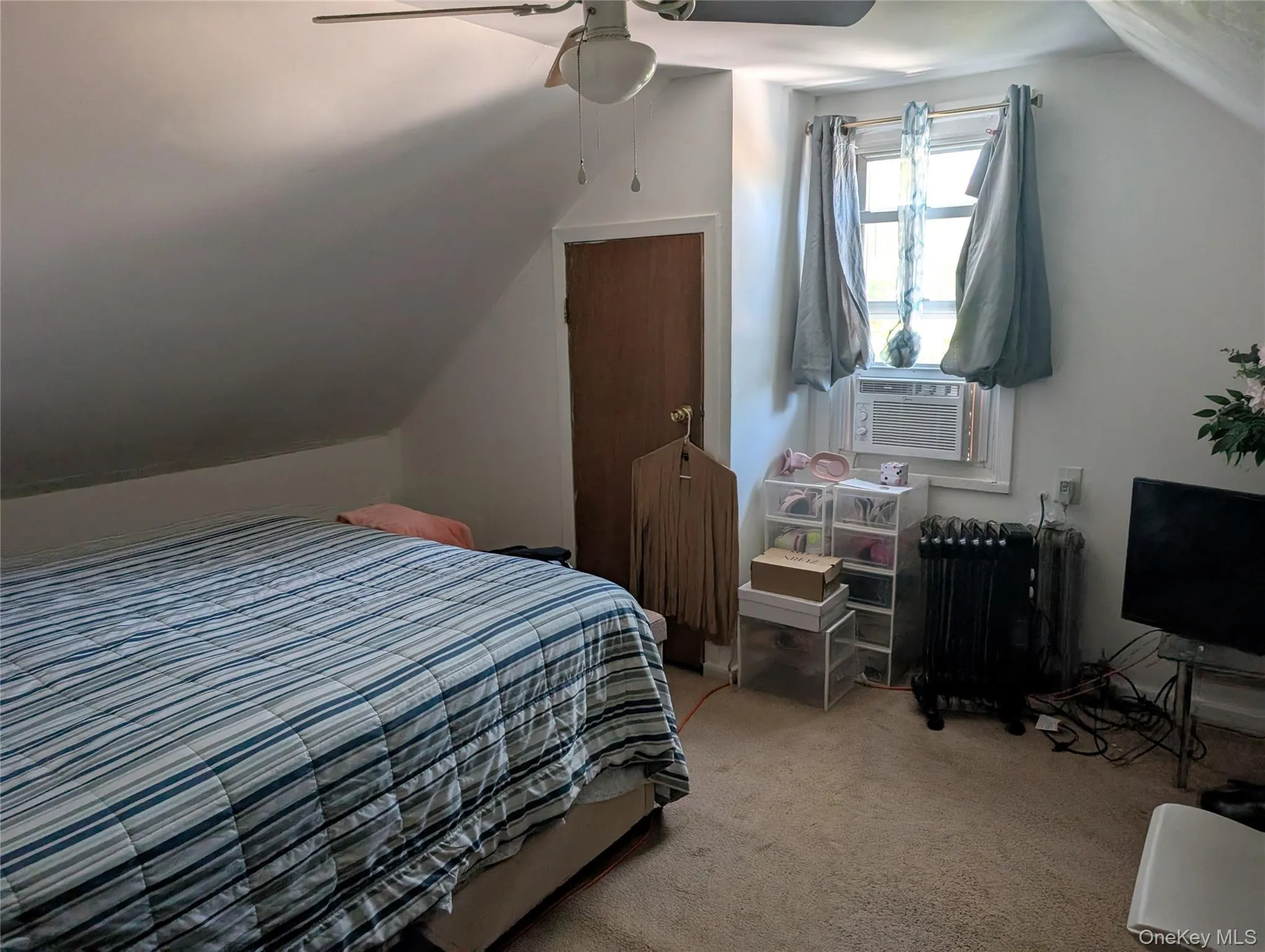Carpeted bedroom featuring lofted ceiling, ceiling fan, and cooling unit Carpeted bedroom featuring lofted ceiling, ceiling fan, and cooling unit