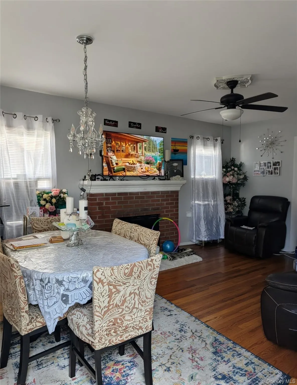 Dining space with a fireplace, wood finished floors, a chandelier, and a ceiling fan Dining space with a fireplace, wood finished floors, a chandelier, and a ceiling fan